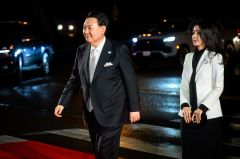 South Korea's President Yoon Suk Yeol walks on a red carpet as South Korea's First Lady Kim Keon Hee walks behind him.