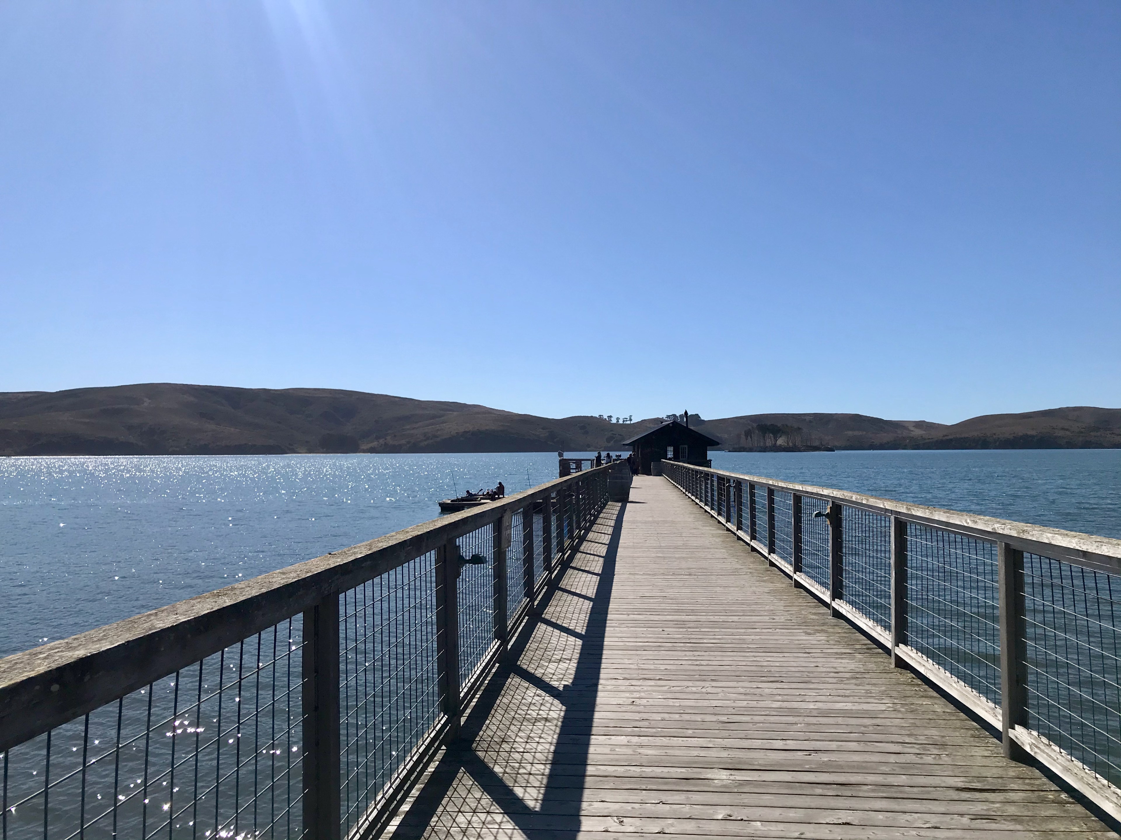 A pier with water in the background against a blue sky.