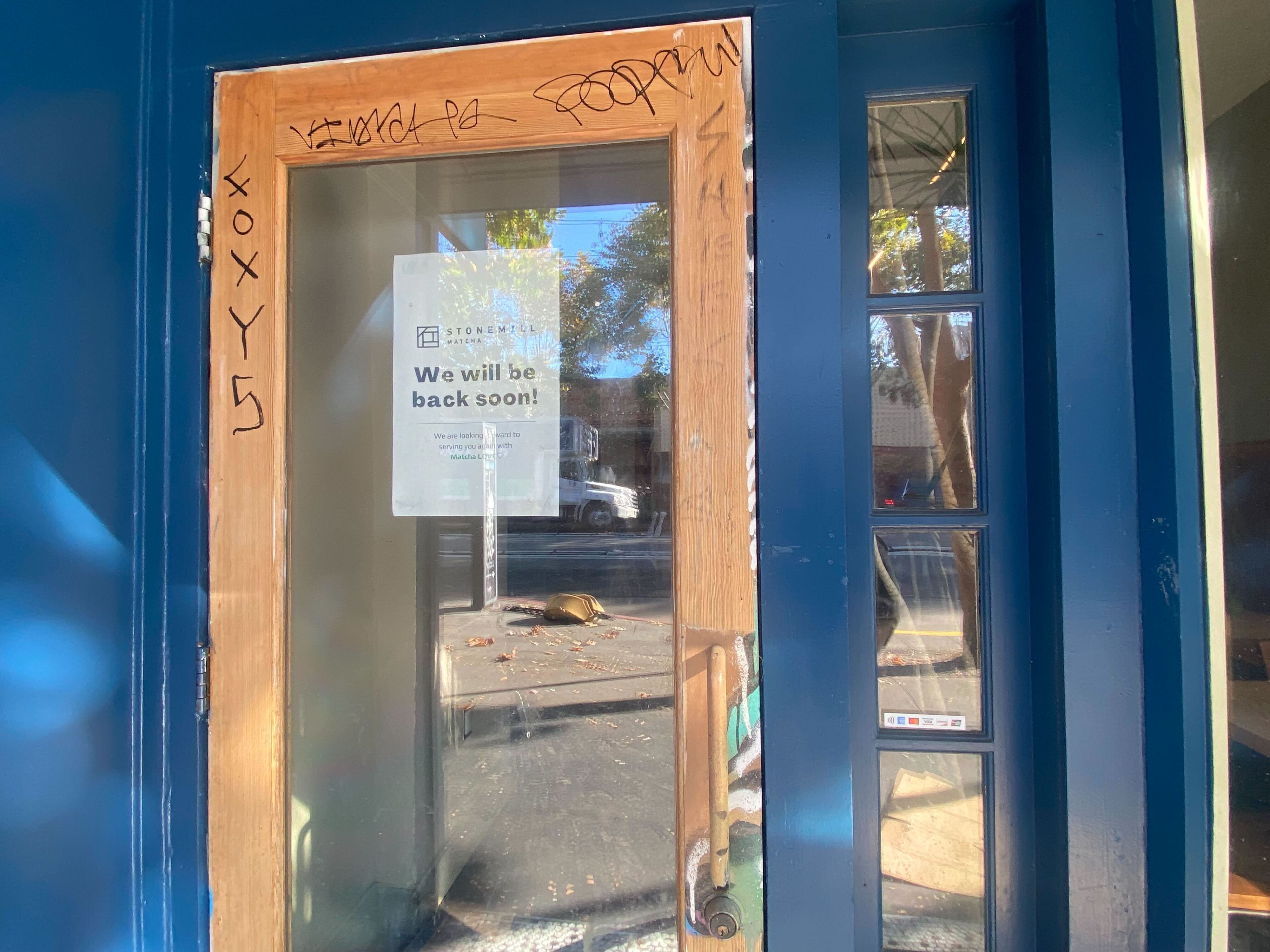 the door of a coffee shop shows a sign that signals the store will reopen soon