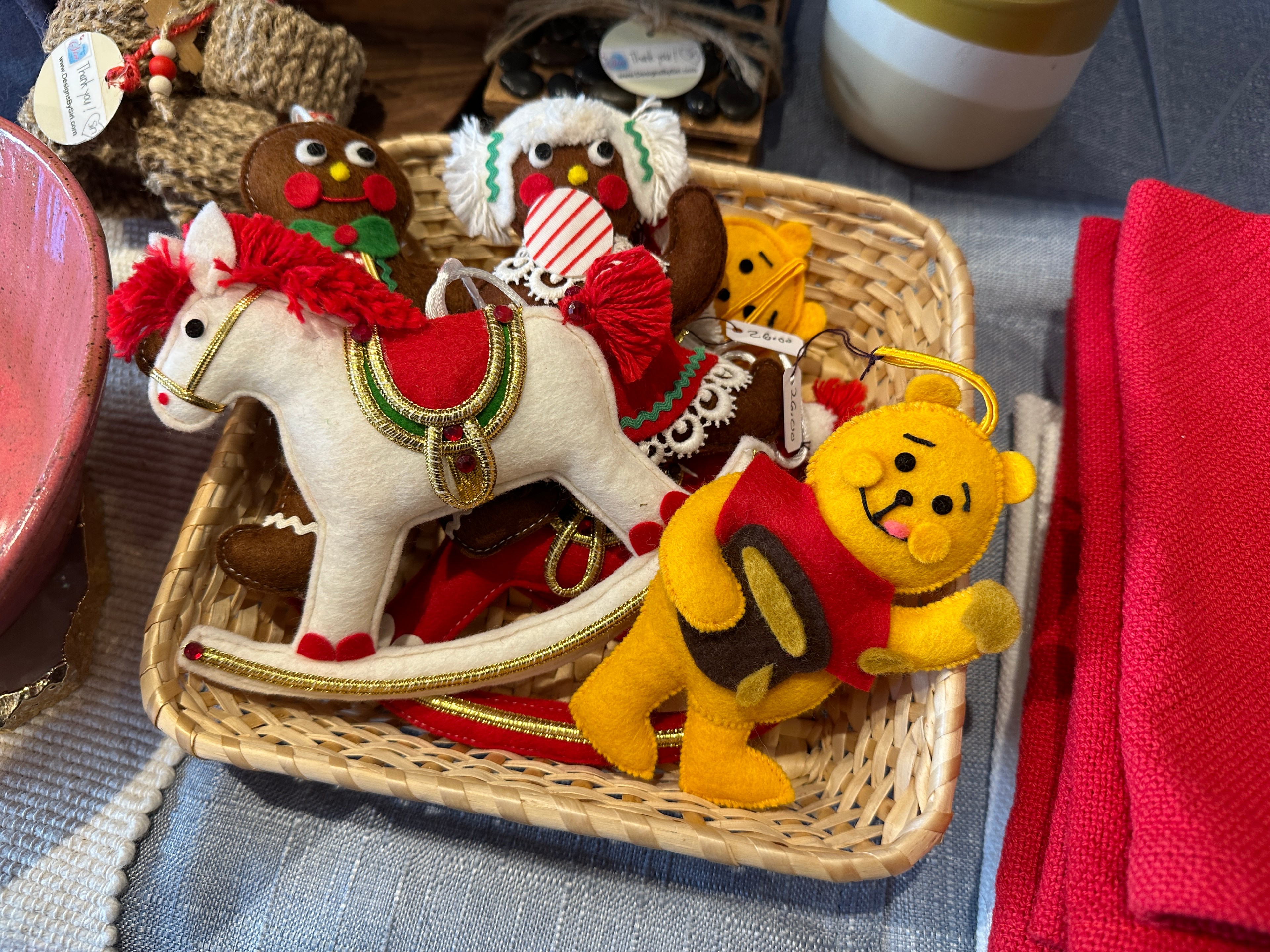 Vintage hand-sewn ornaments, including a rocking horse and Winnie the Pooh bear sit in a basket. 