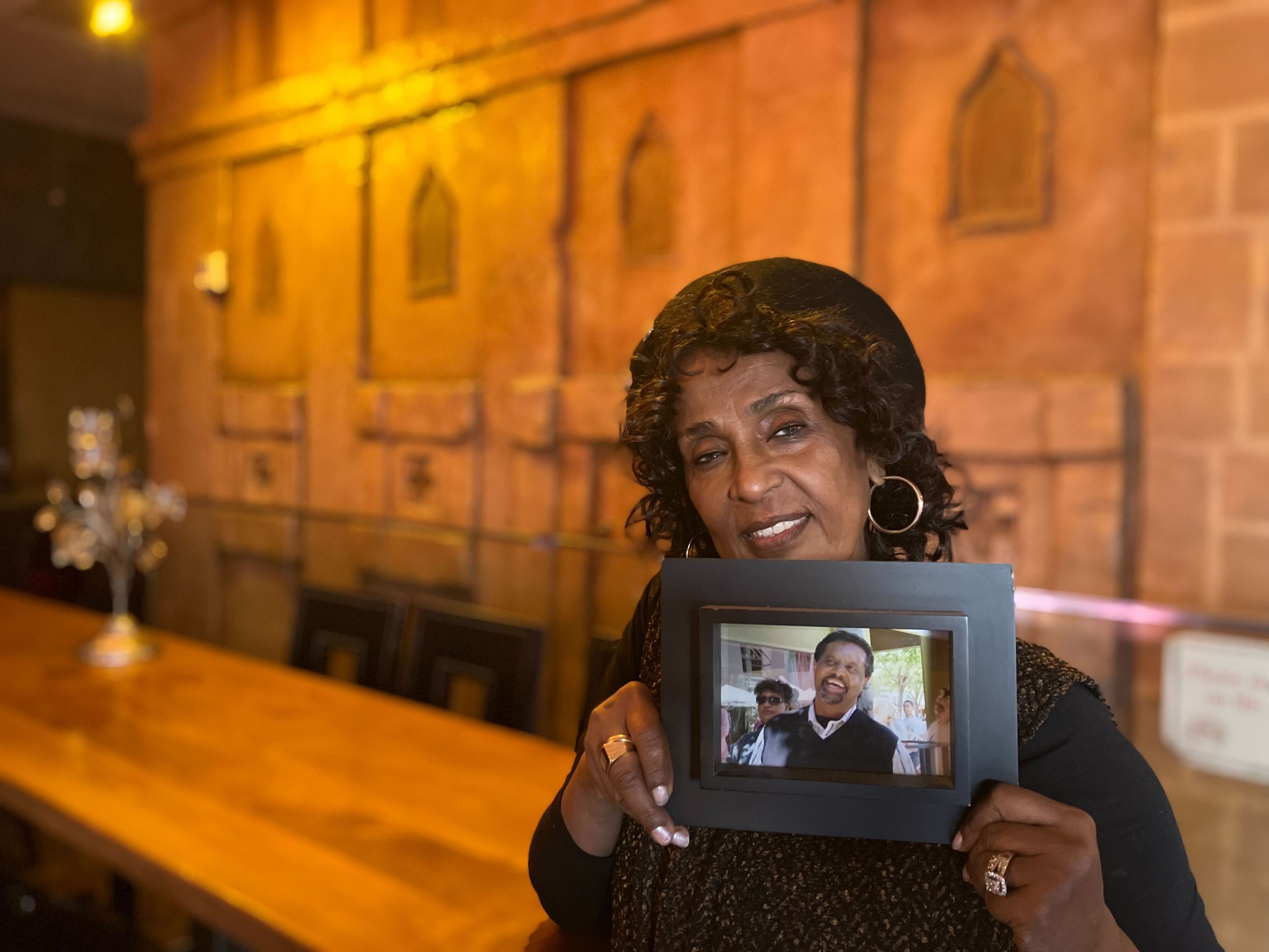 Net Alemayehu—owner of the Sheba Piano Lounge and wife of the late Agonafer Shiferaw—stands with a portrait of her husband in her lounge. Shiferaw, who owned the historic Rasselas Jazz Club in the Fillmore District for 26 years, died on Nov. 11, 2023 after an over year-long battle with cancer.