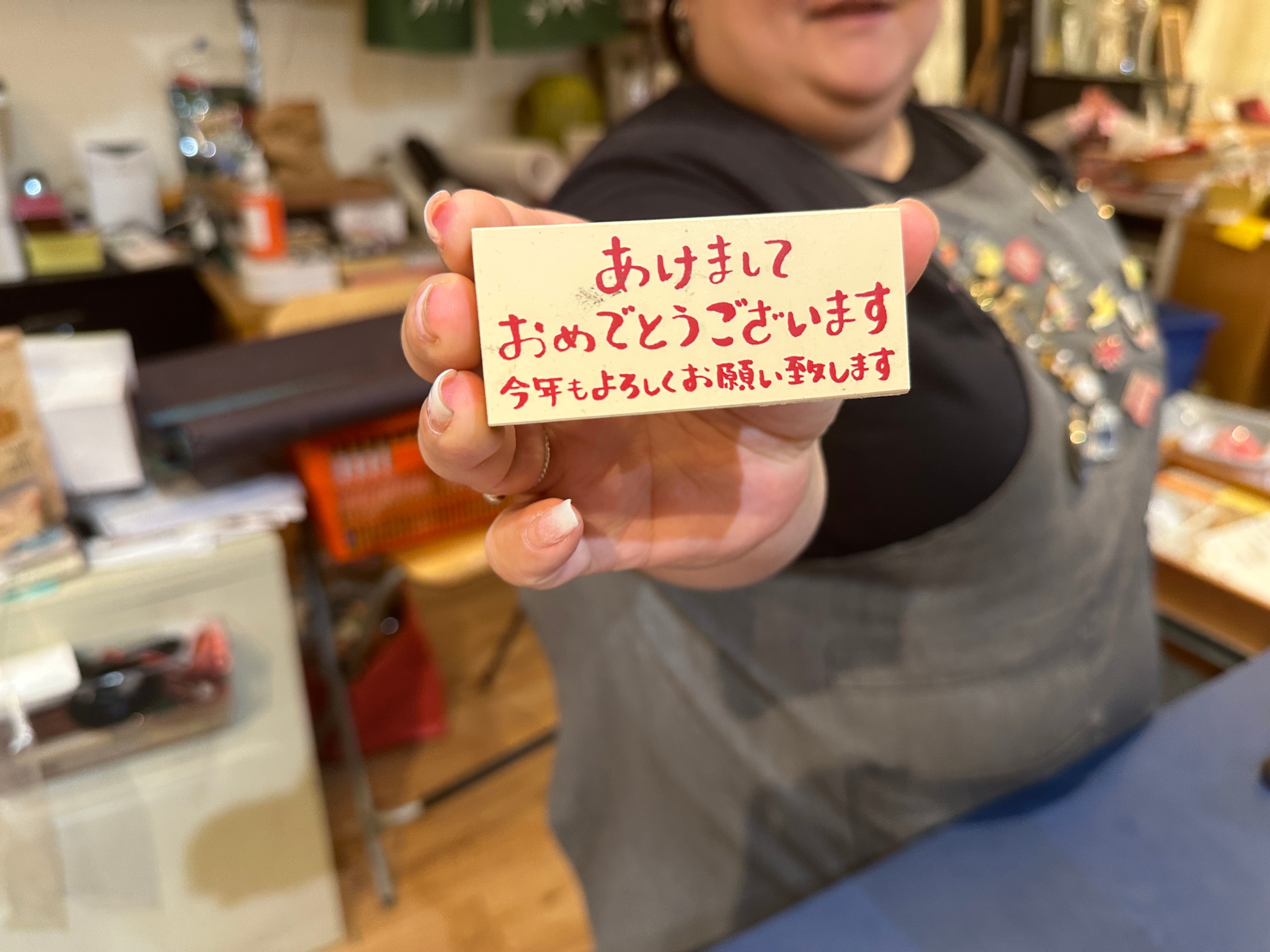 Paper Tree retail associate Hitomi Silver holds up a Japanese &quot;Happy New Year&quot; stamp.  