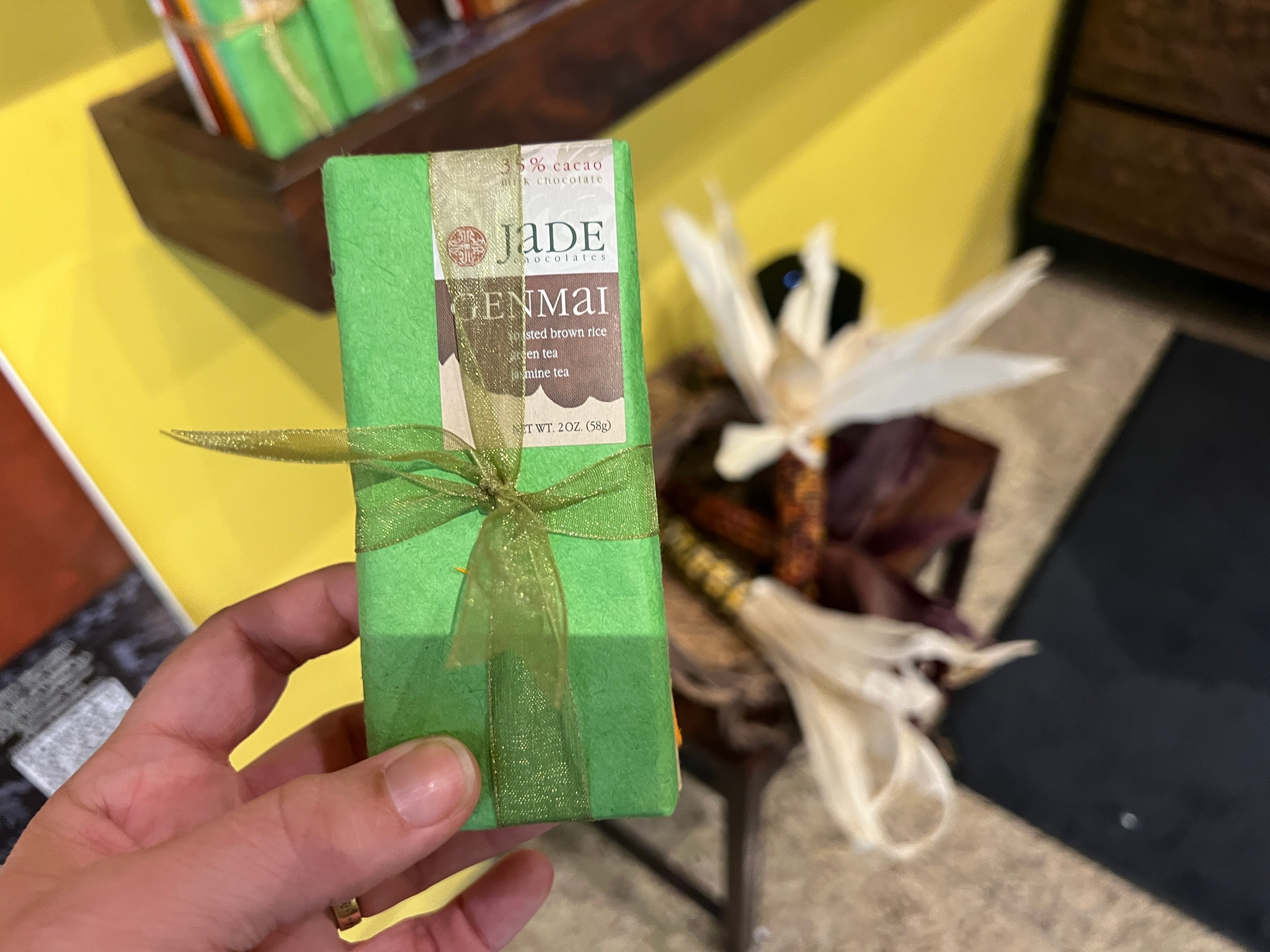 A green-wrapped chocolate bar is tied with a golden ribbon. 