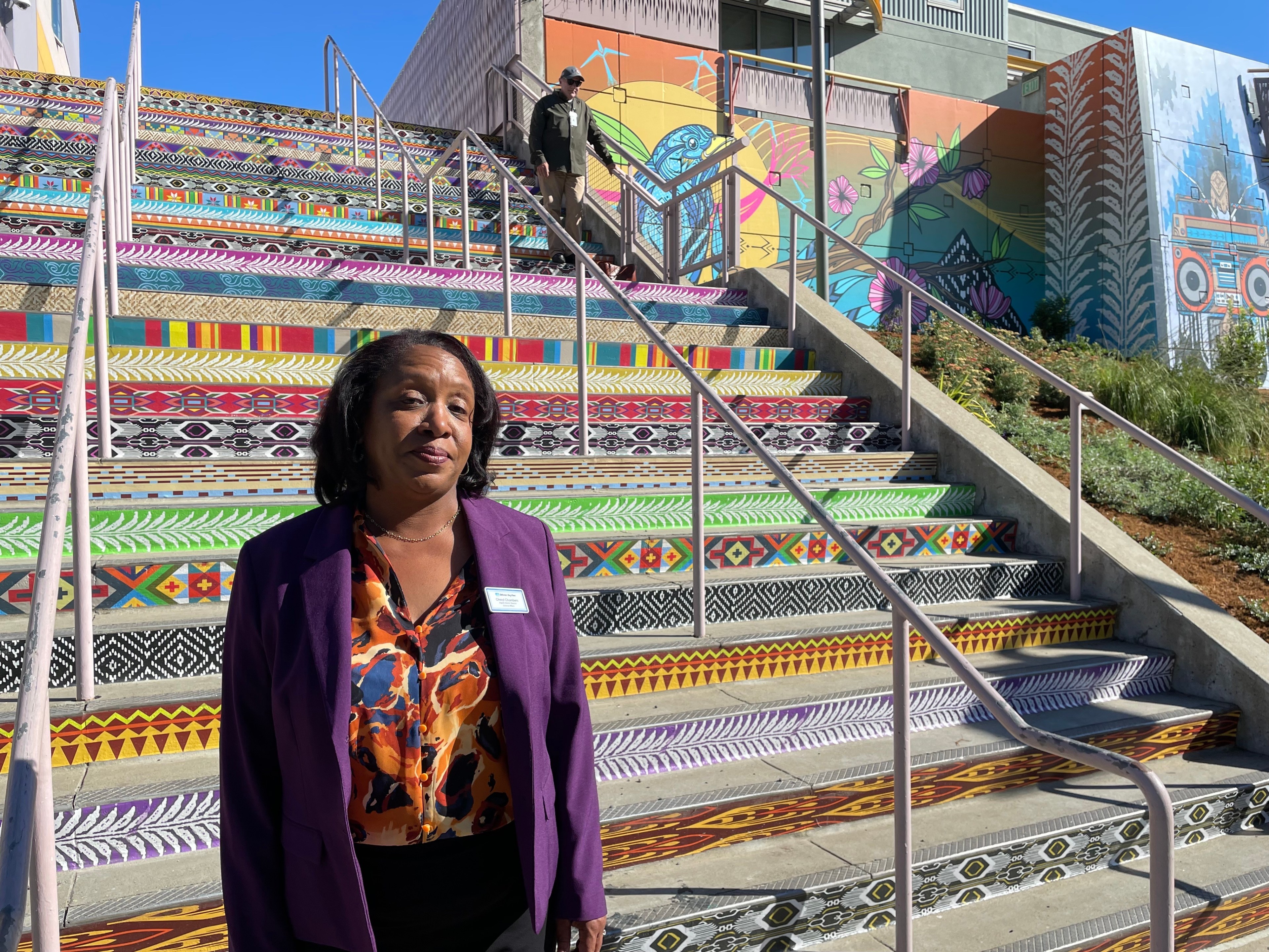 A woman stands in front of a multi-colored staircase.