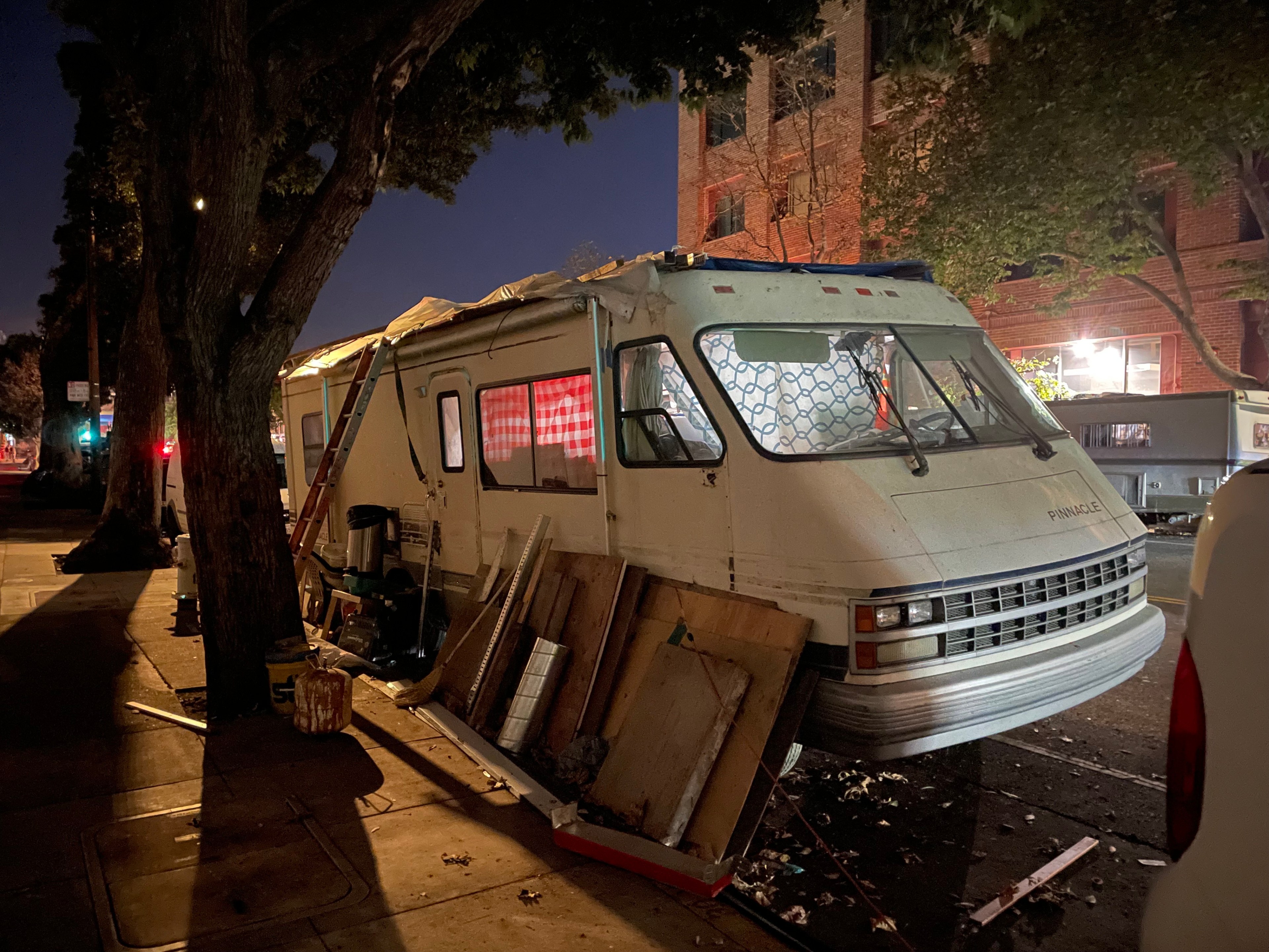 An RV is seen parked on a street.
