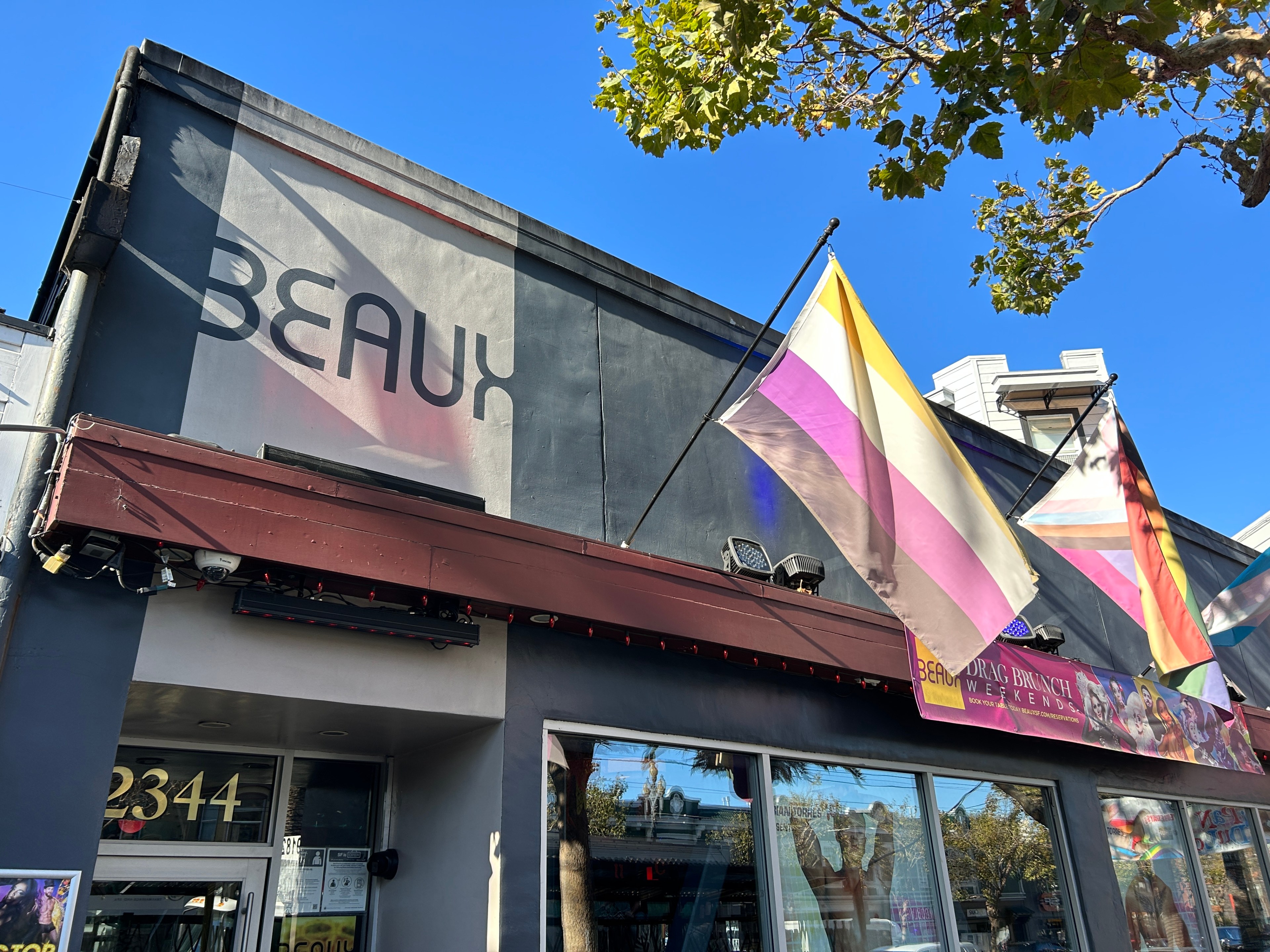 The exterior of a bar is seen in the Castro with various LGBTQ+ pride flag.
