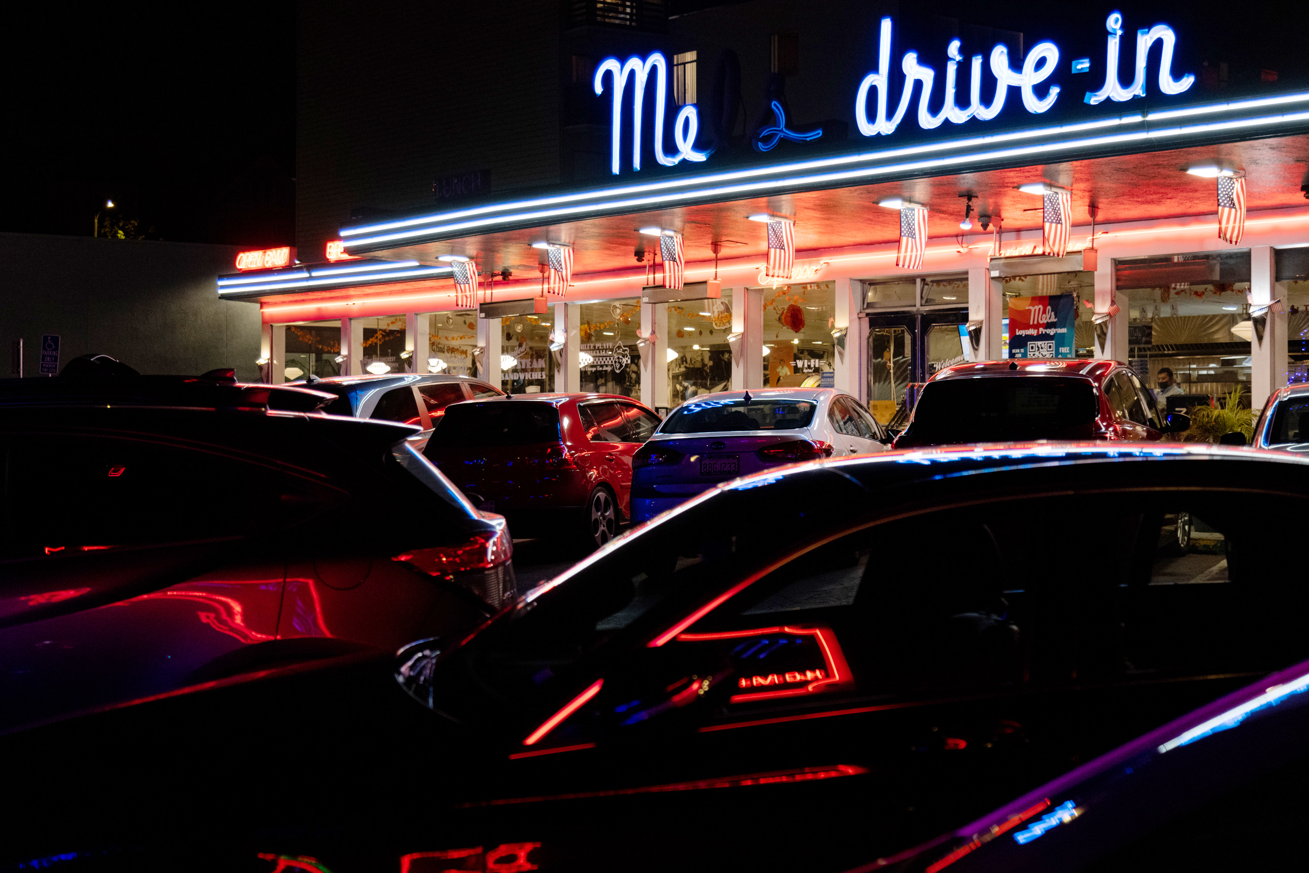 A neon sign at night with the words &quot;Mels Drive-in&quot;
