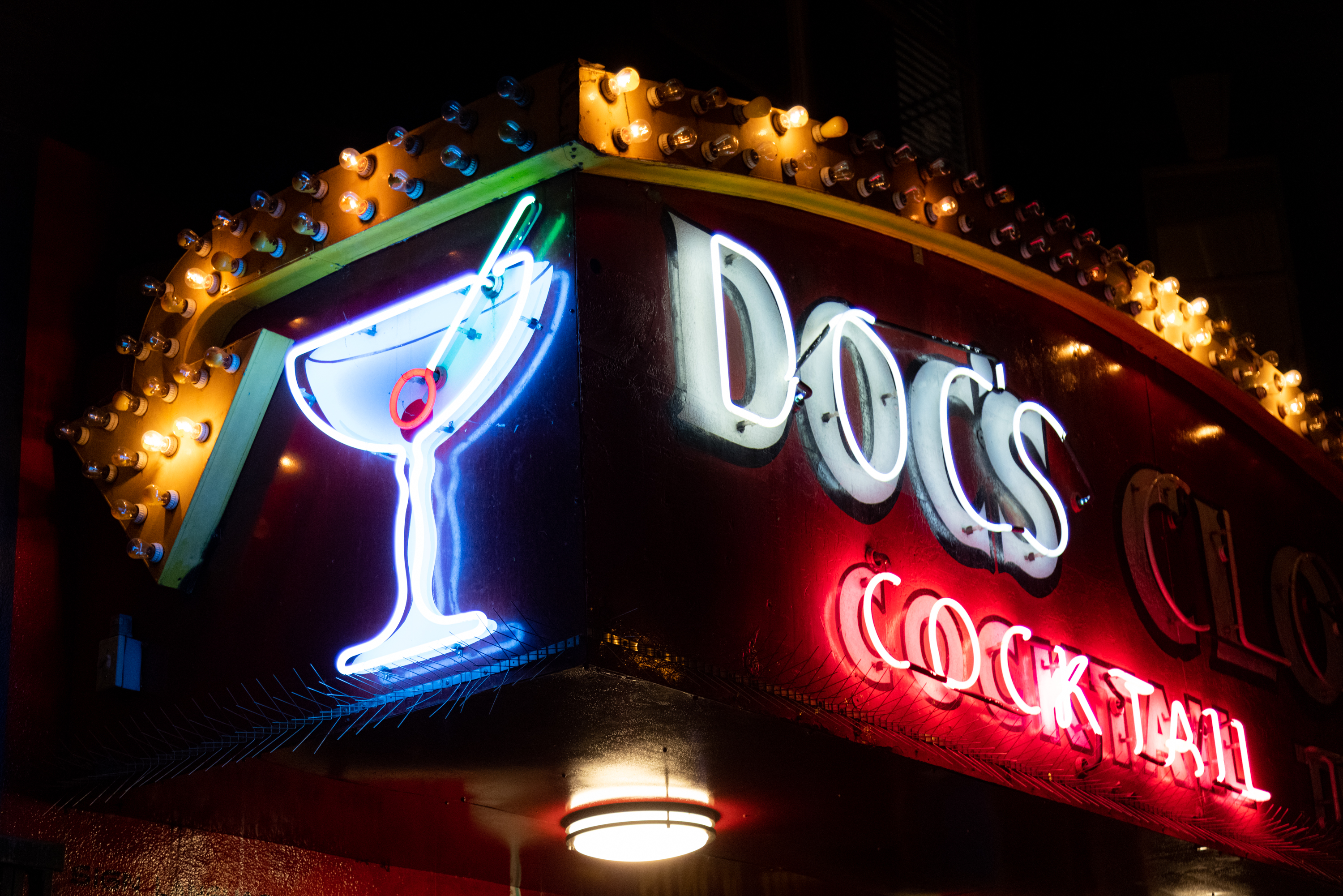 A multicolored neon sign at night with the words &quot; DOC’s COCKTAIL&quot;