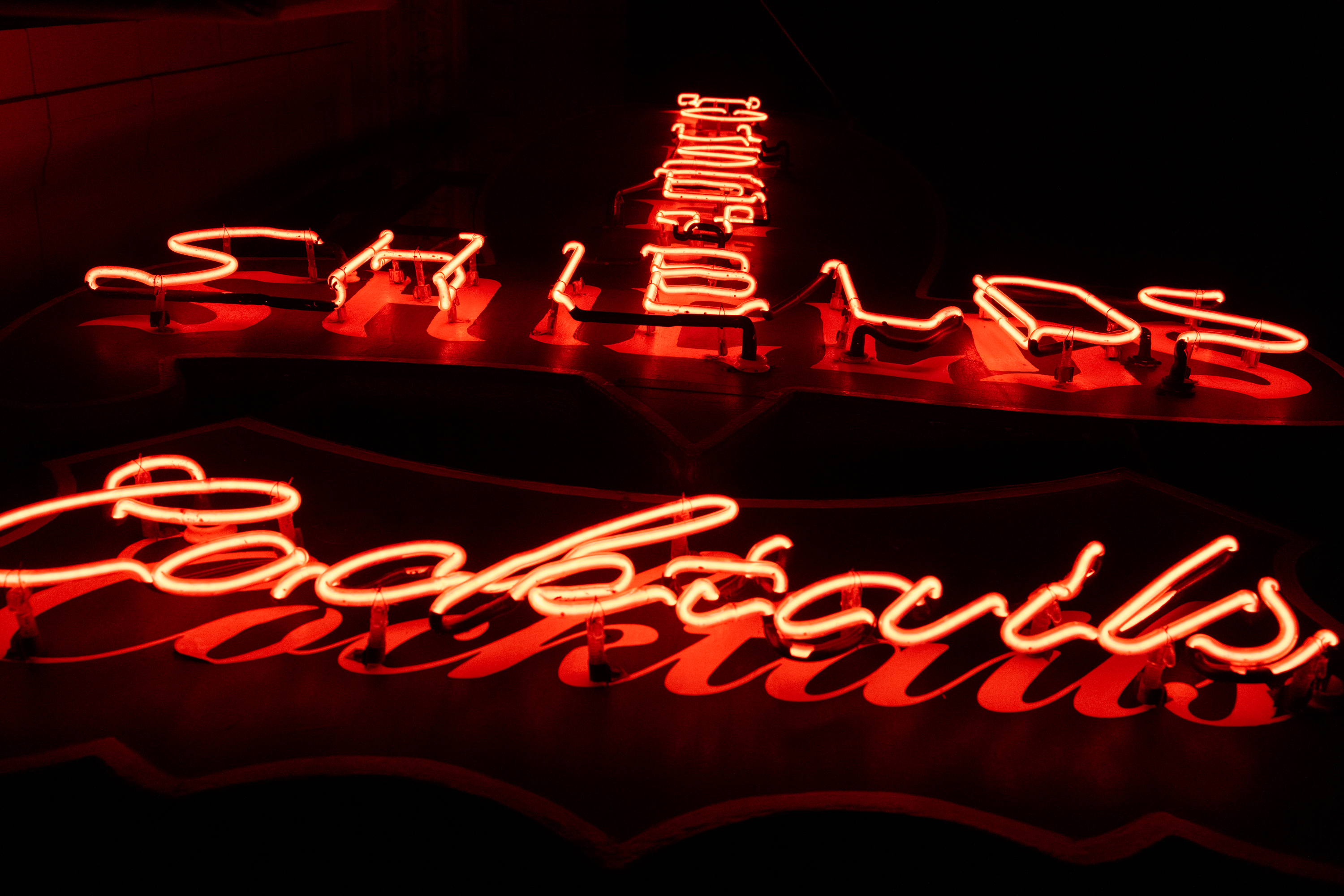 A red neon sign at night with the words &quot;The House of Shields Cocktails&quot;