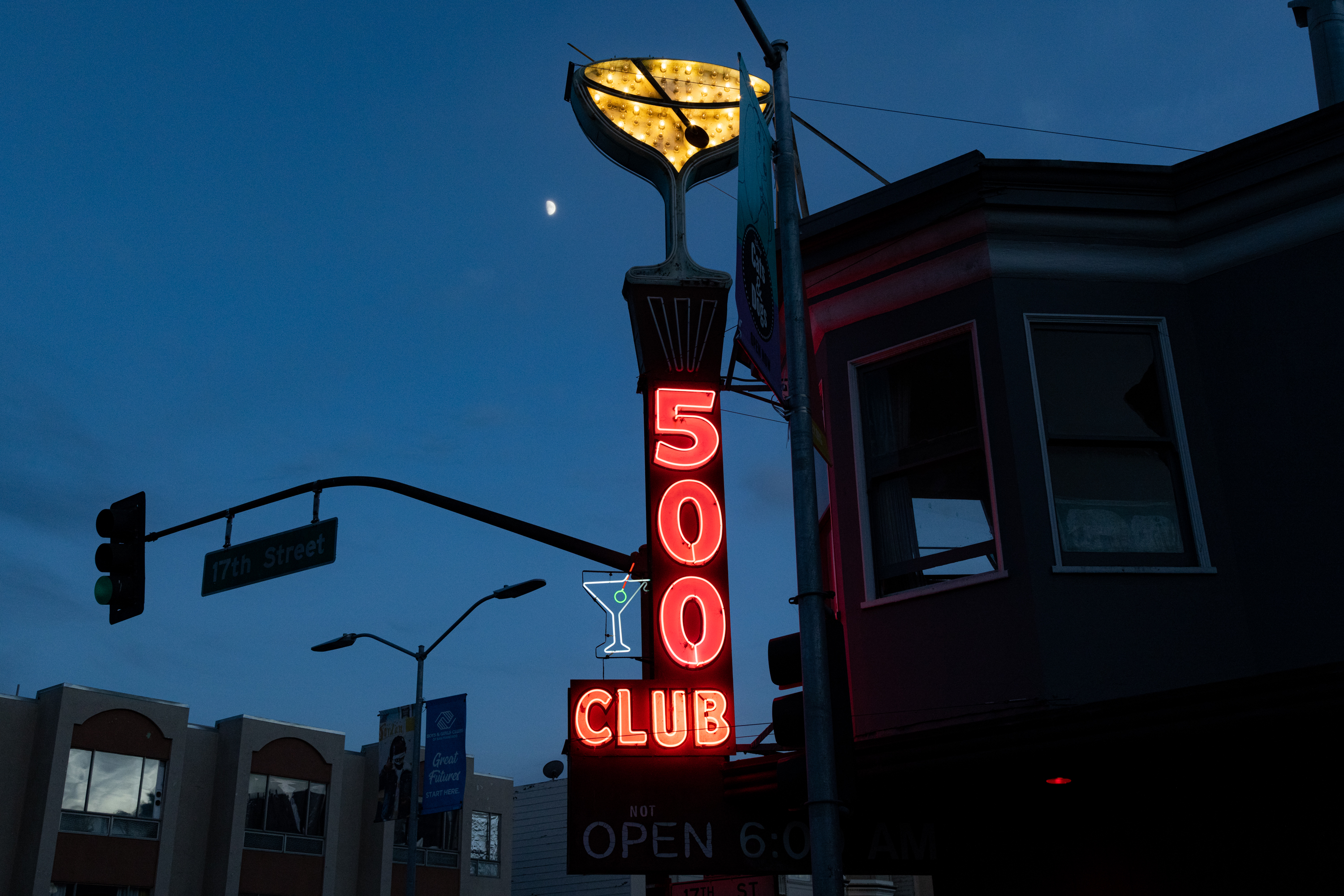 A neon sign at night with a large cocktail glass on top with the words &quot;500 Club&quot; towards the bottom