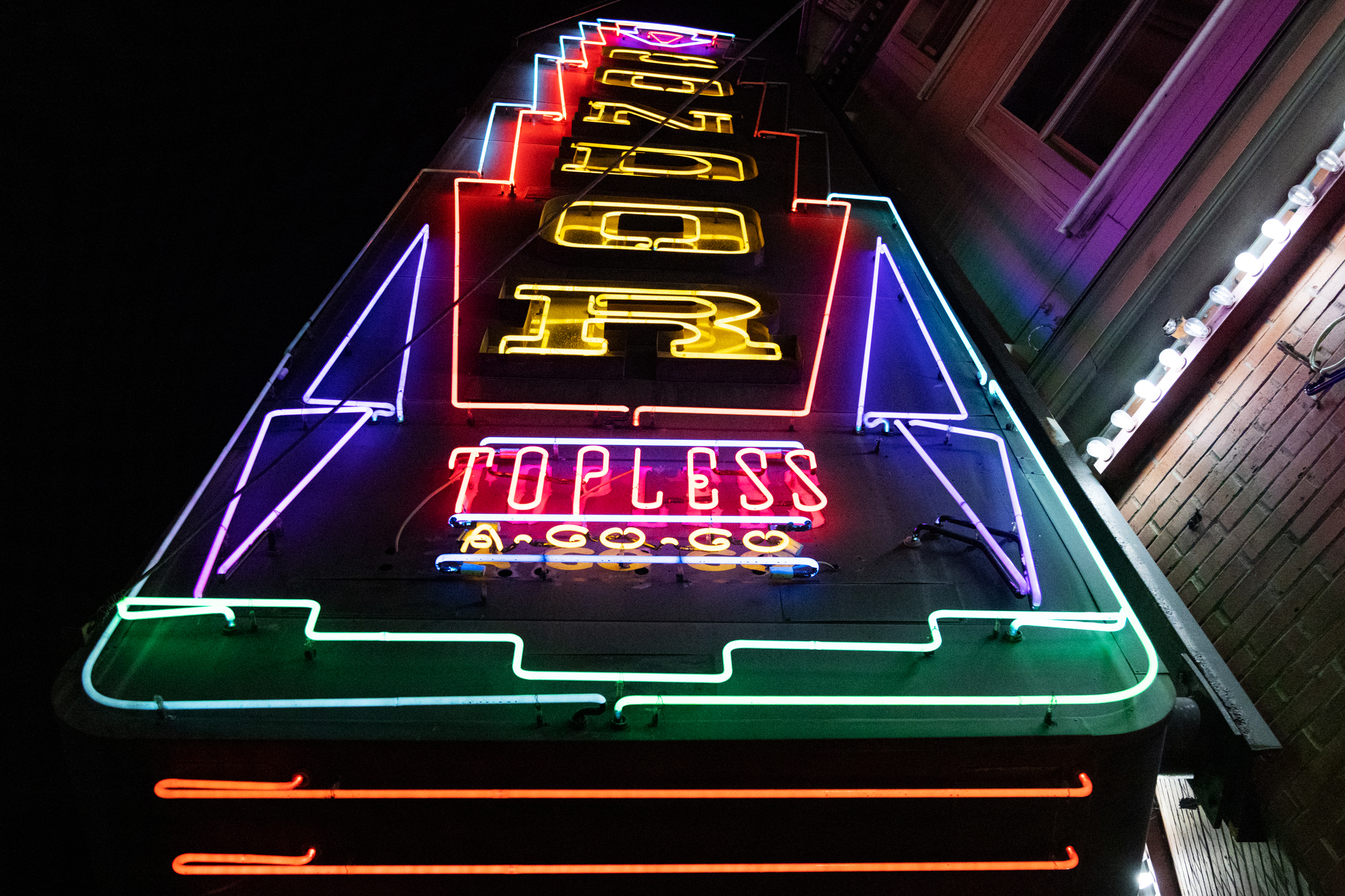 A neon sign at night with the words &quot;TOPLESS A GO GO&quot; and &quot;Condor&quot; on a tall neon sign.