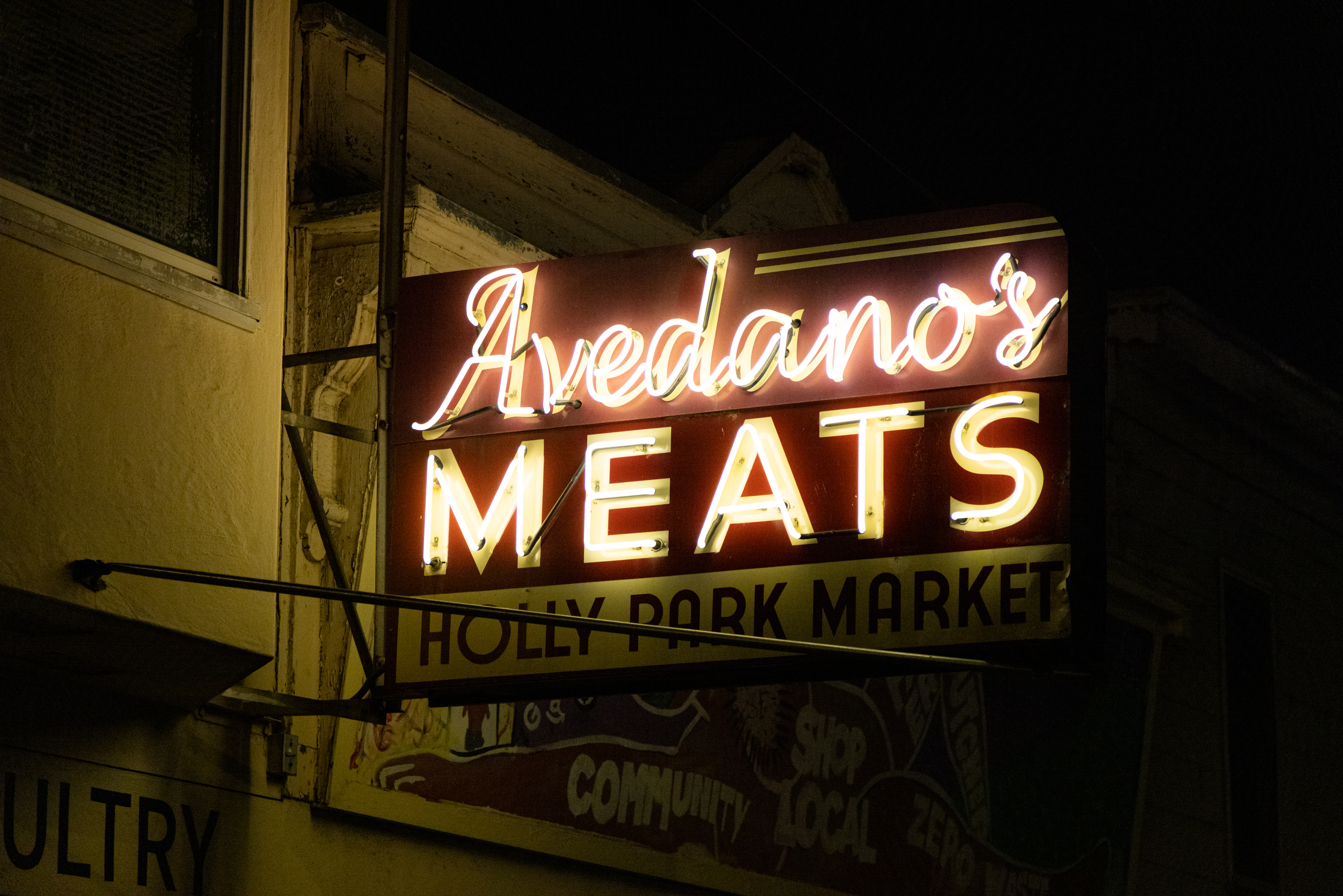 A neon sign at night that reads &quot;Avedano's MEATS&quot;