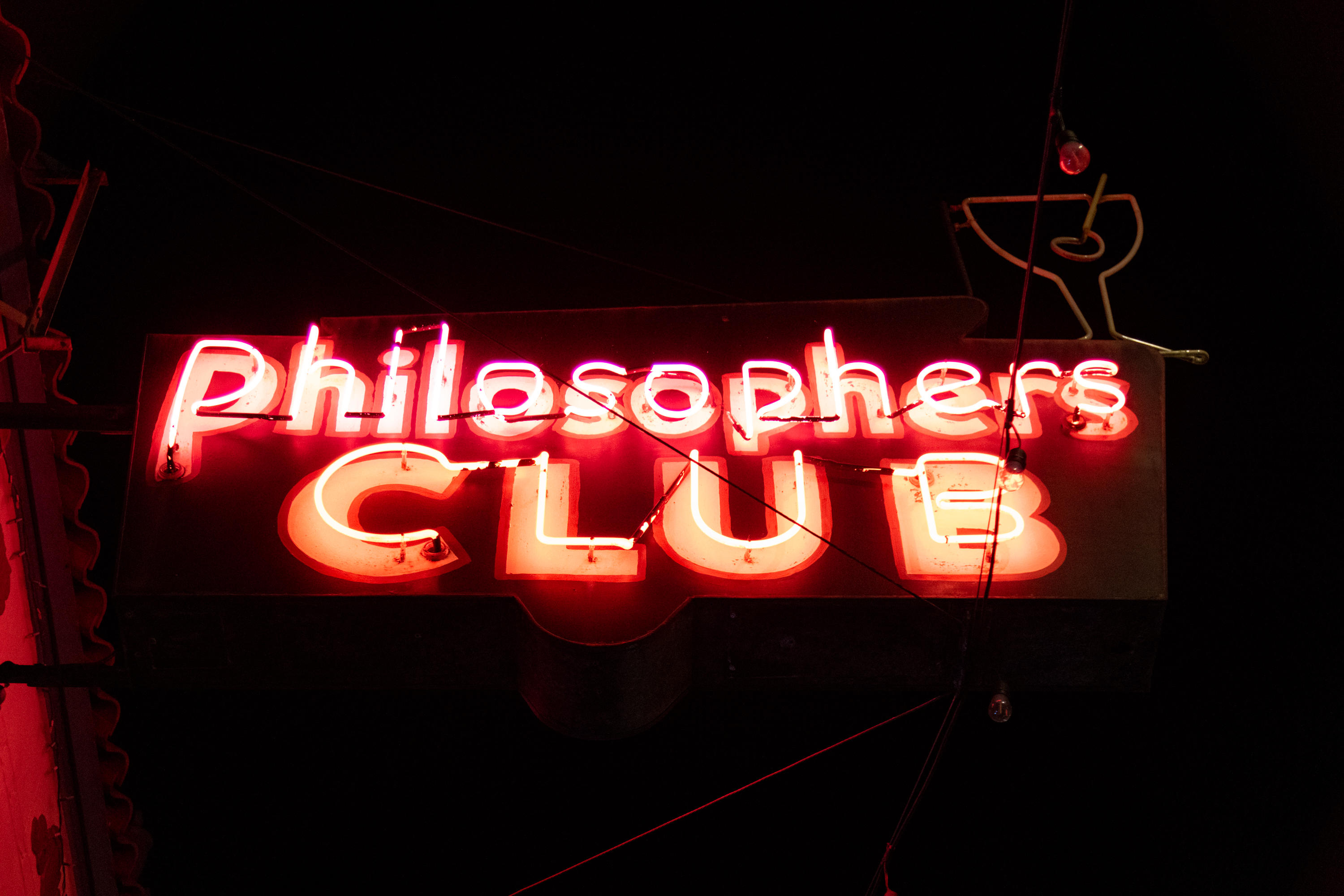 A red neon sign at night that reads &quot;Philosopher's CLUB&quot;