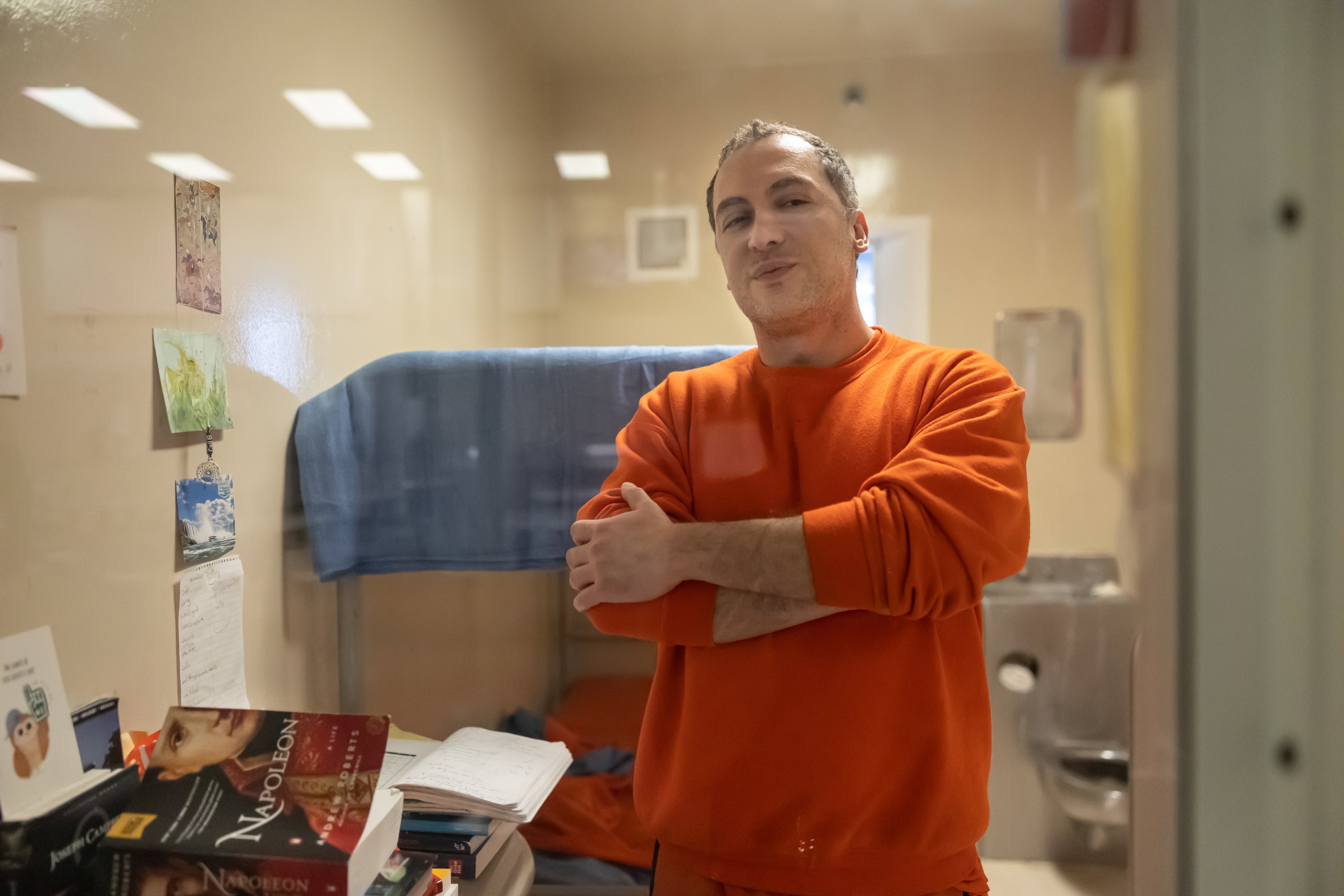 Jail inmate Nima Momeni, suspect for the killing of Cash App founder Bob Lee, while dressed in an orange sweatshirt and sweatpants crosses his arms while looking out the window of his jail cell.