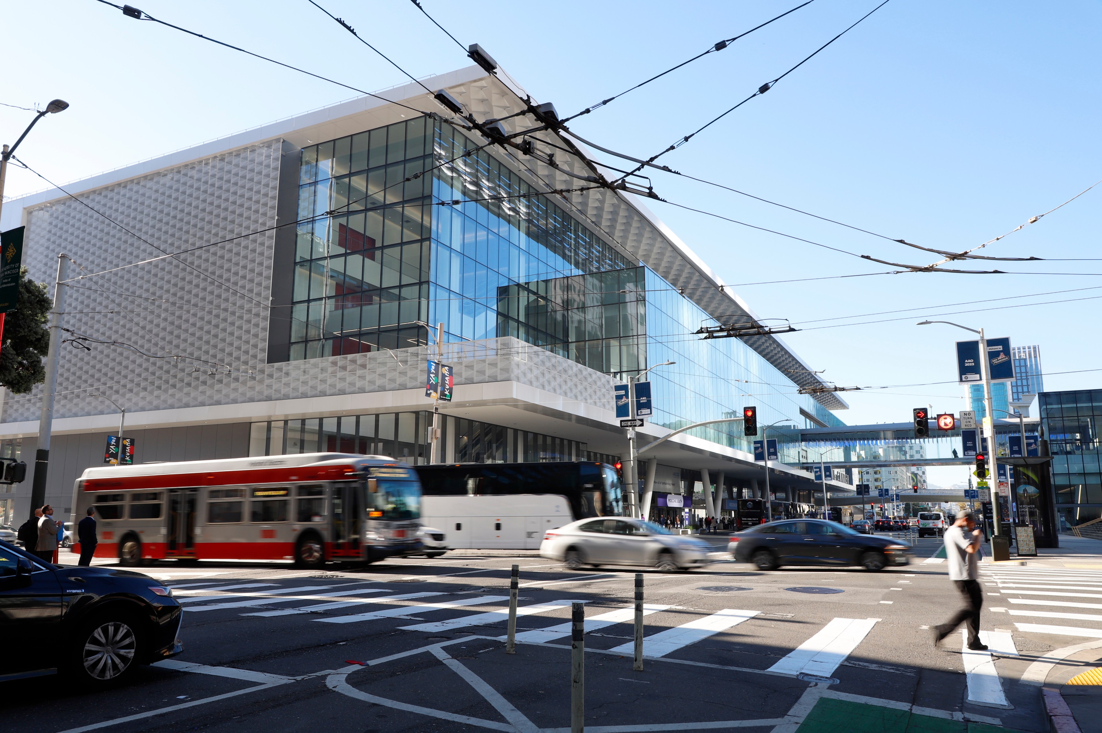 Buses and automobiles speed up 3rd street while pedestrians cross a busy intersection with the glass-enclosed Moscone Center in the background in downtown San Francisco. The area will look less busy when the City implements security ahead of APEC at Moscone Center.