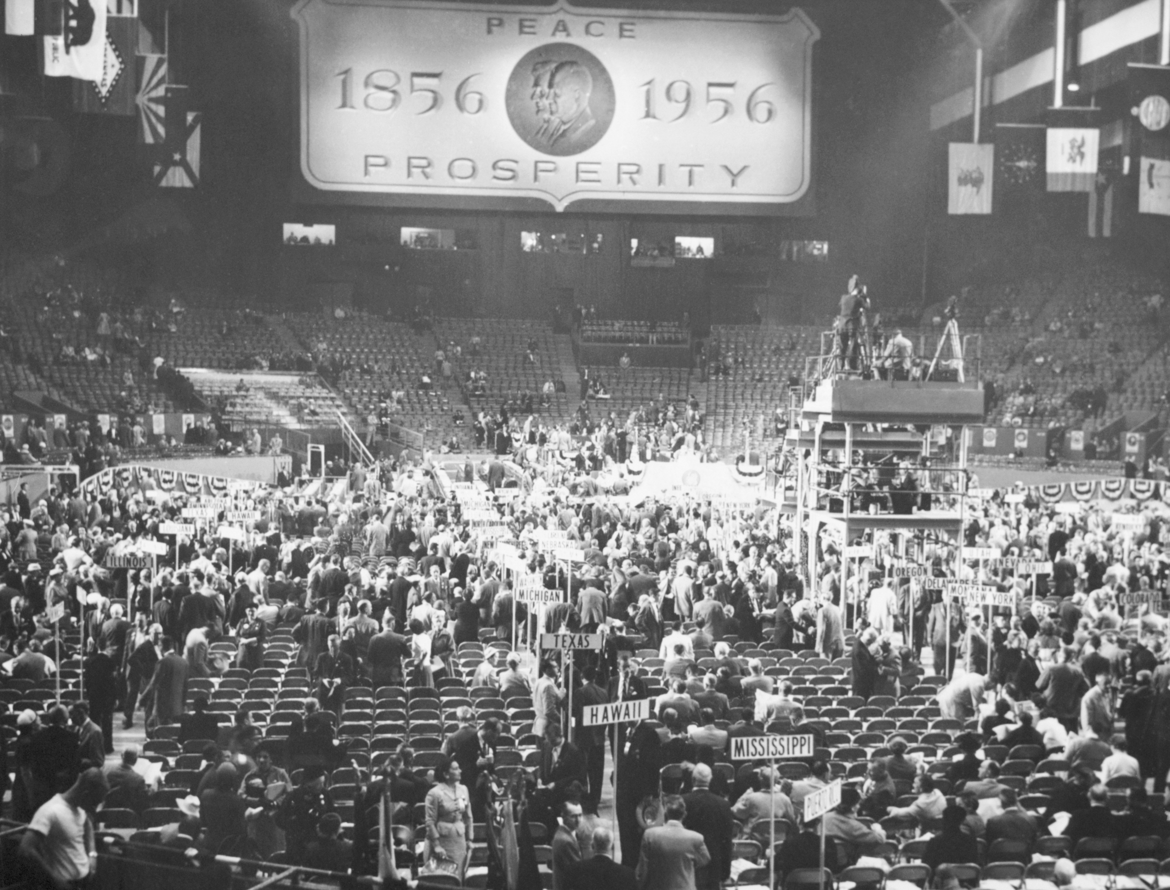 A large arena roughly half-filled has a large sign that reads &quot;PEACE 1859 1956 PROSPERITY&quot; during the Republican National Convention at the Cow Palace.
