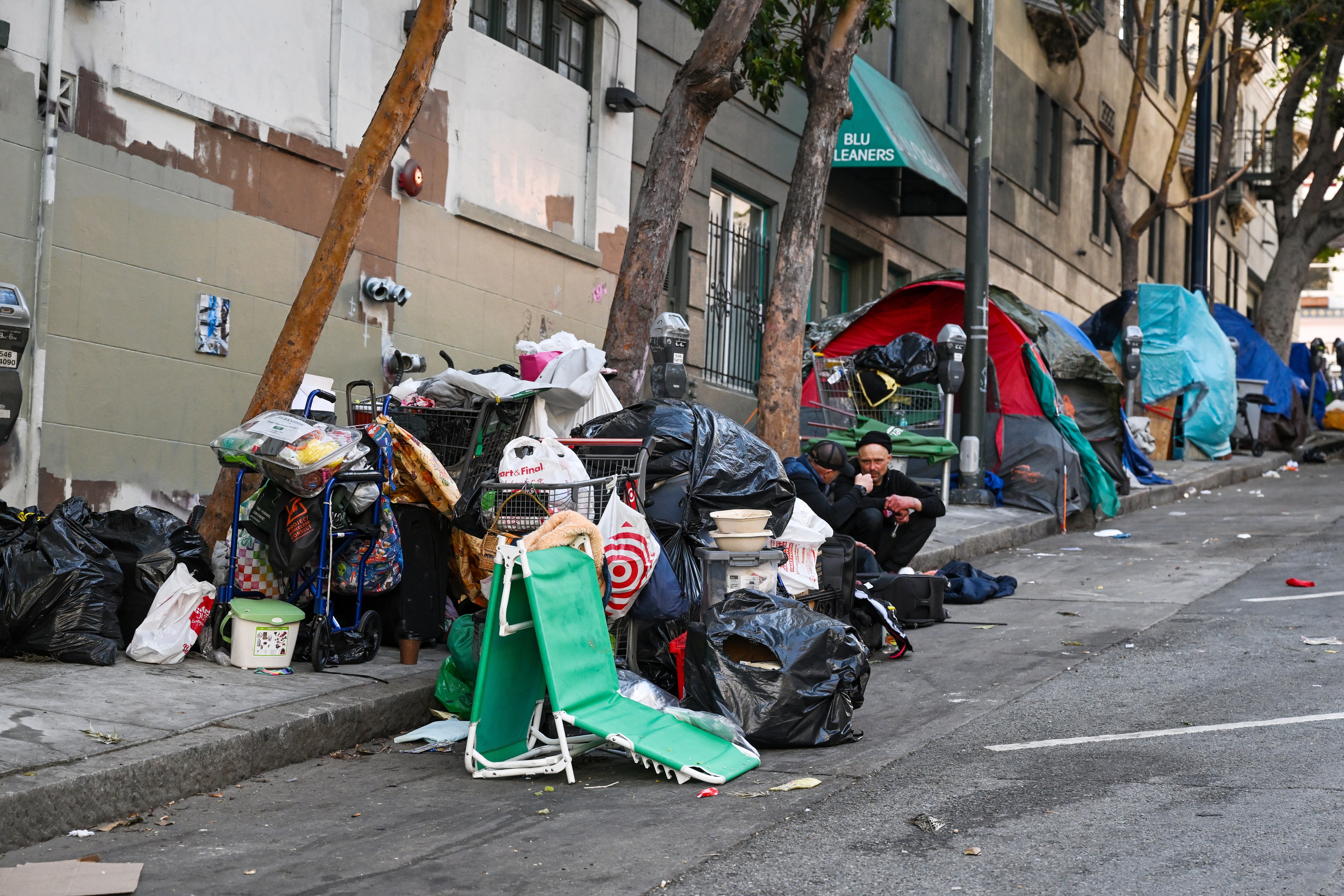 A collection of personal belongings and tents line a city street.