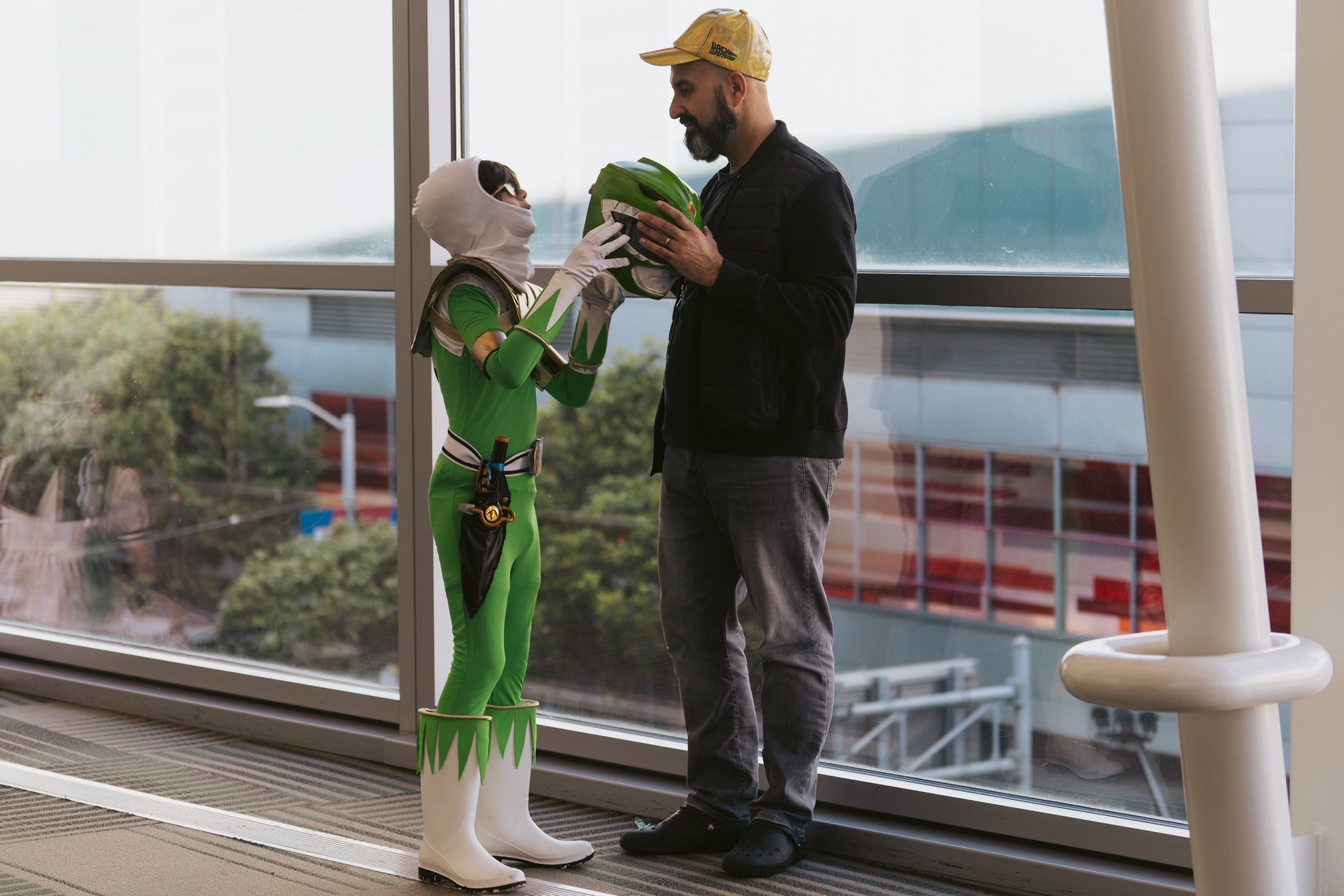 A child dresses as a superhero hands their mask to a man during a cos play event.
