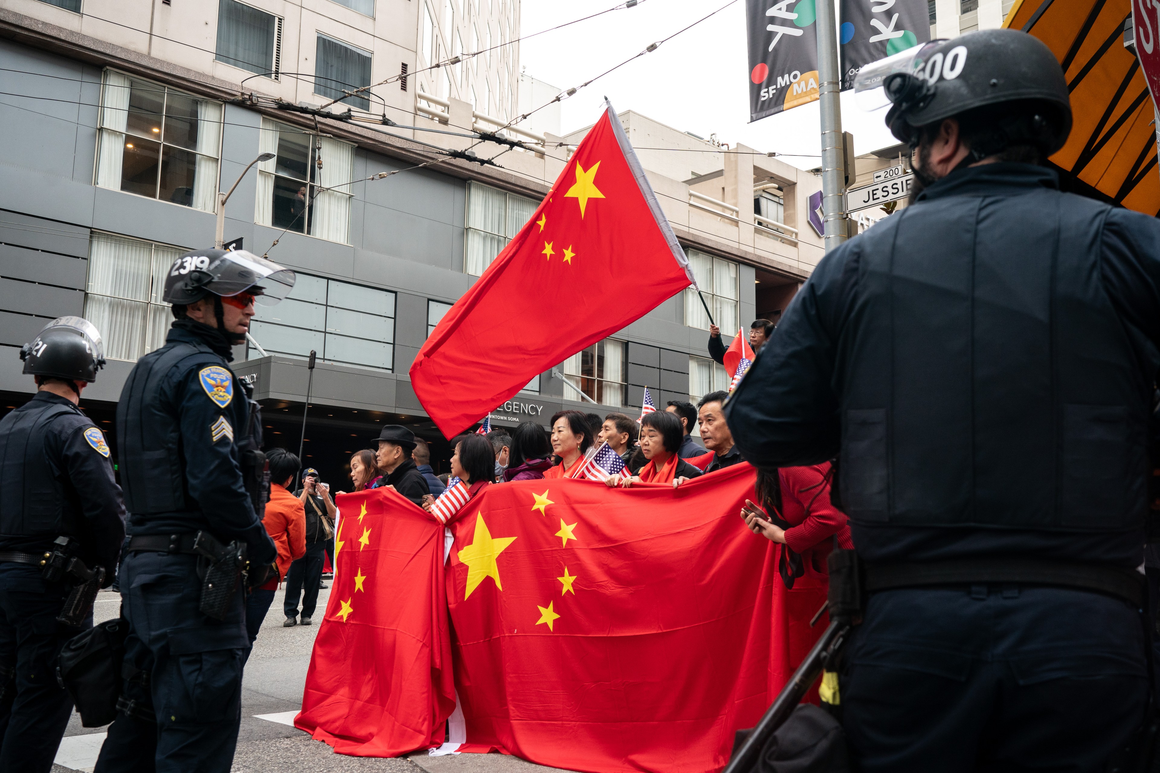 Chinese supporters stand on the side of the street with police on either side during a demonstration.