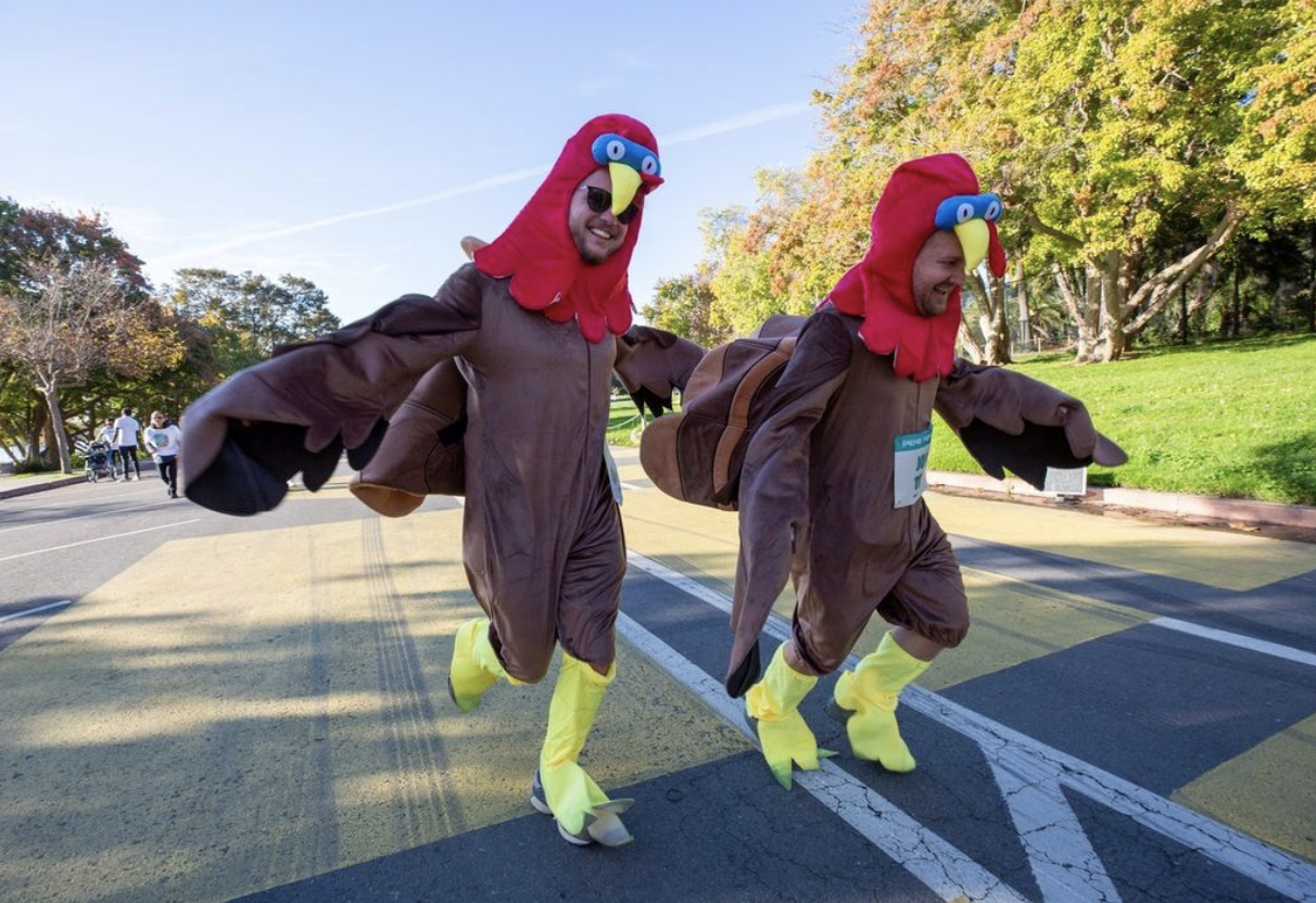 Two men run in turkey suit costumes. 