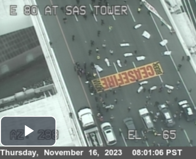 A banner reading &quot;ceasefire&quot; is laid on the pavement of the Bay Bridge as anti-war protesters block traffic in a photo captured from high on the bridge.