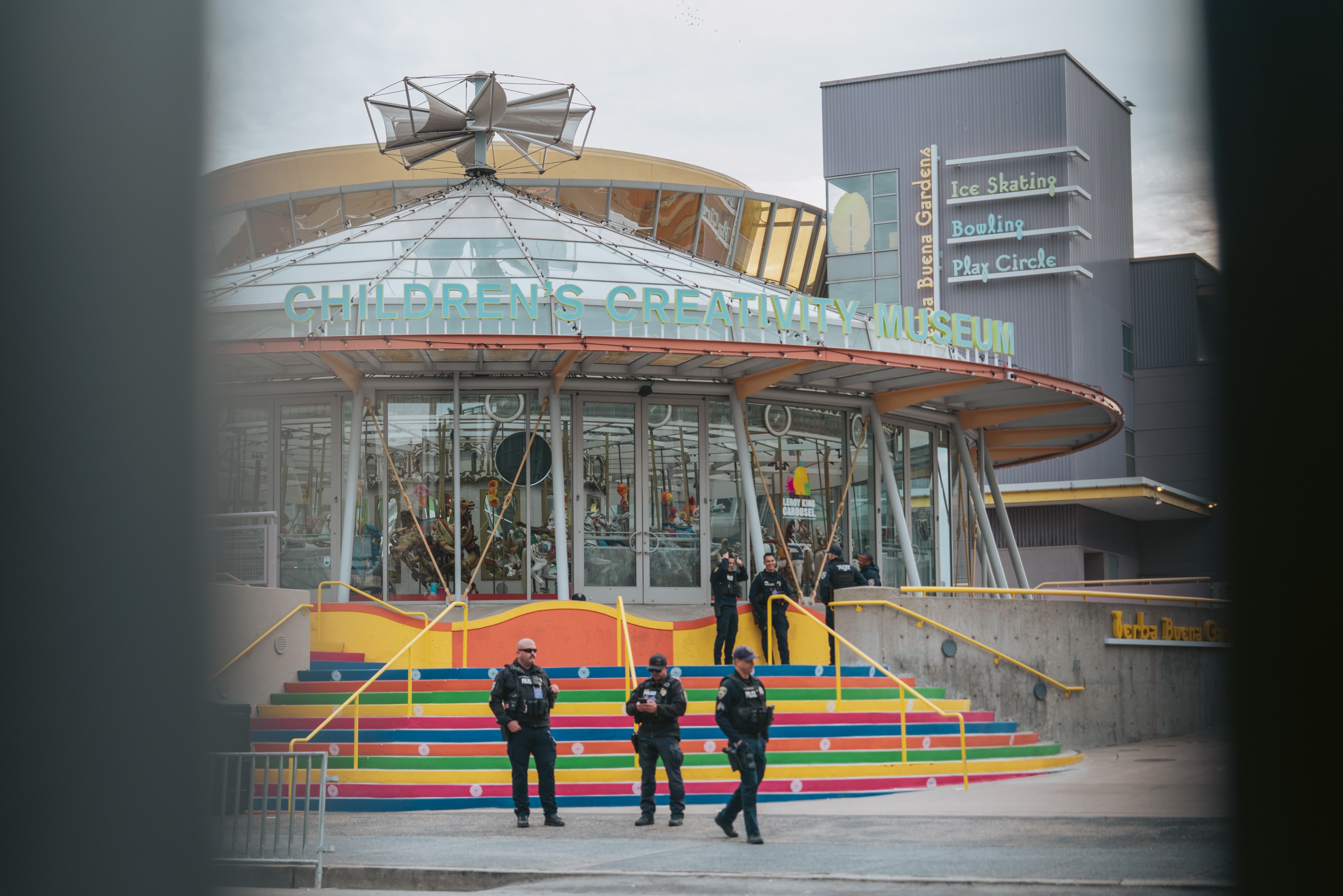 A group of police officers stand near a carousel that reads the Children's Creativity Musuem.