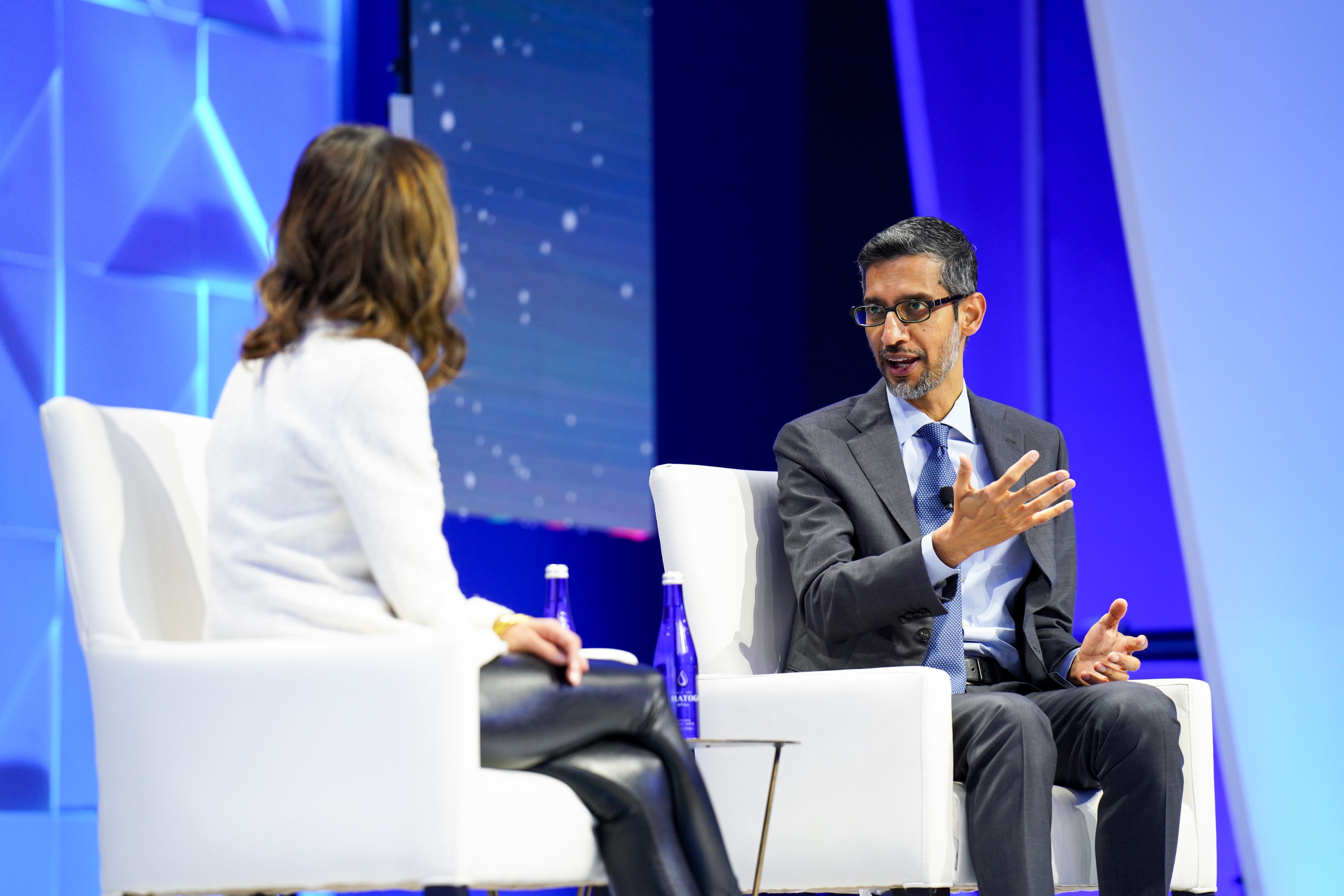 Google and Alphabet CEO Sundar Pichai and Bloomberg's Emily Chang are seated in white chairs mid-conversation at APEC CEO Summit 2023.