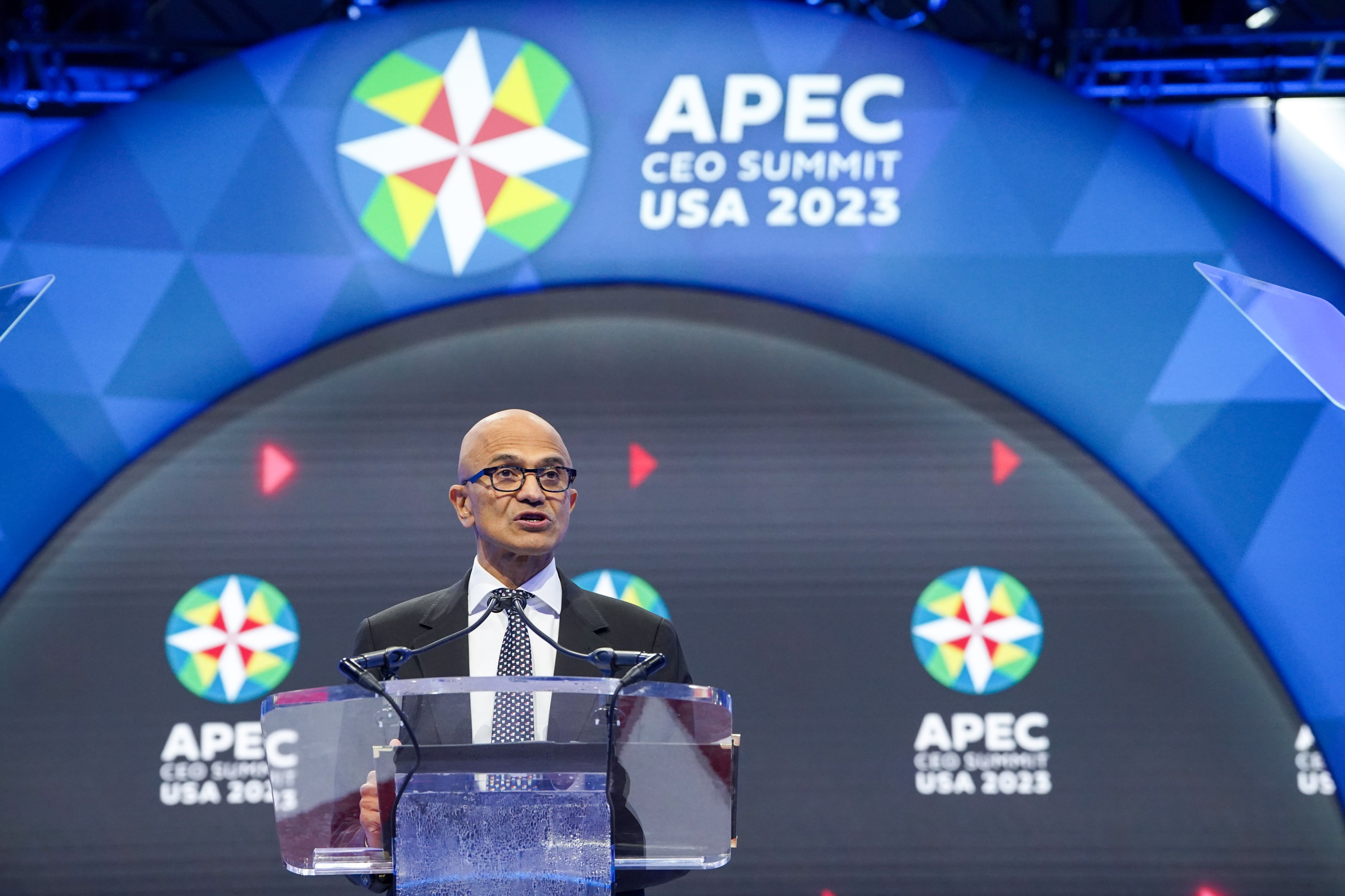 Microsoft CEO Satya Nadella speaks at a clear podium at the APEC CEO Summit in San Francisco.