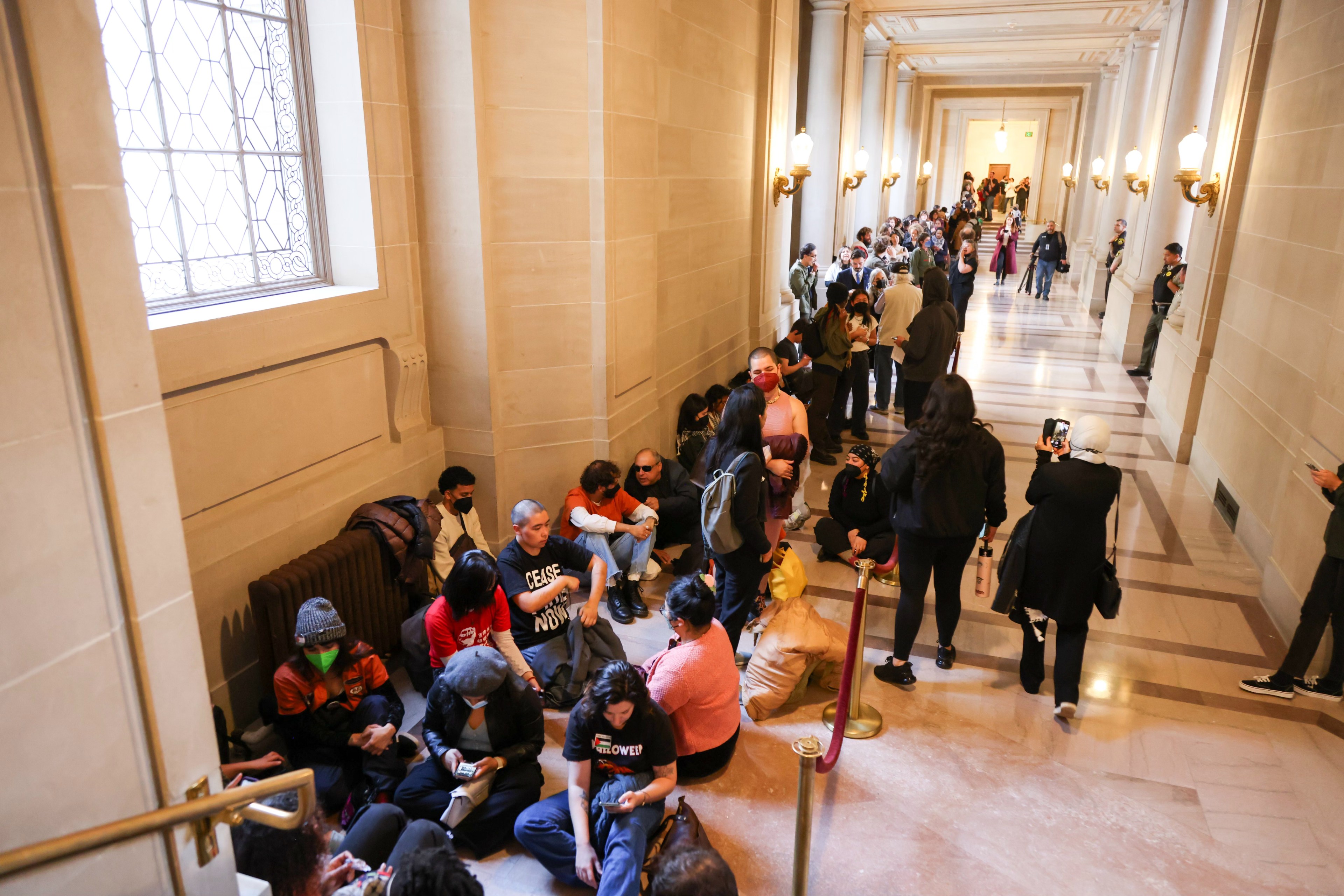 A line of people standing and sitting in city hall.