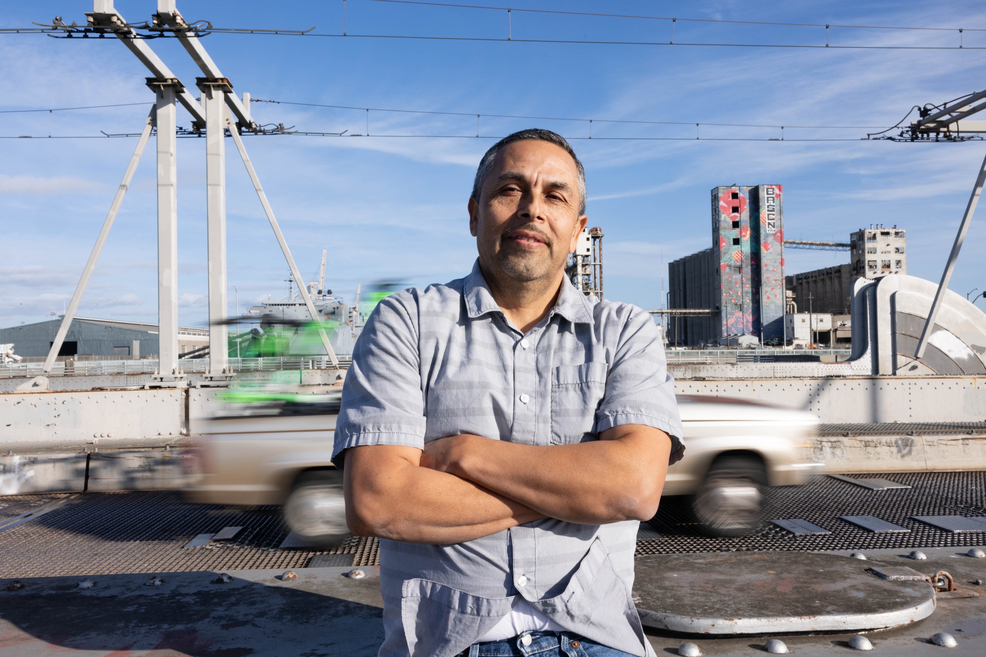 A man Ray Guerrero stands on the Islais Creek Bridge facing the camera while posing for a portrait.