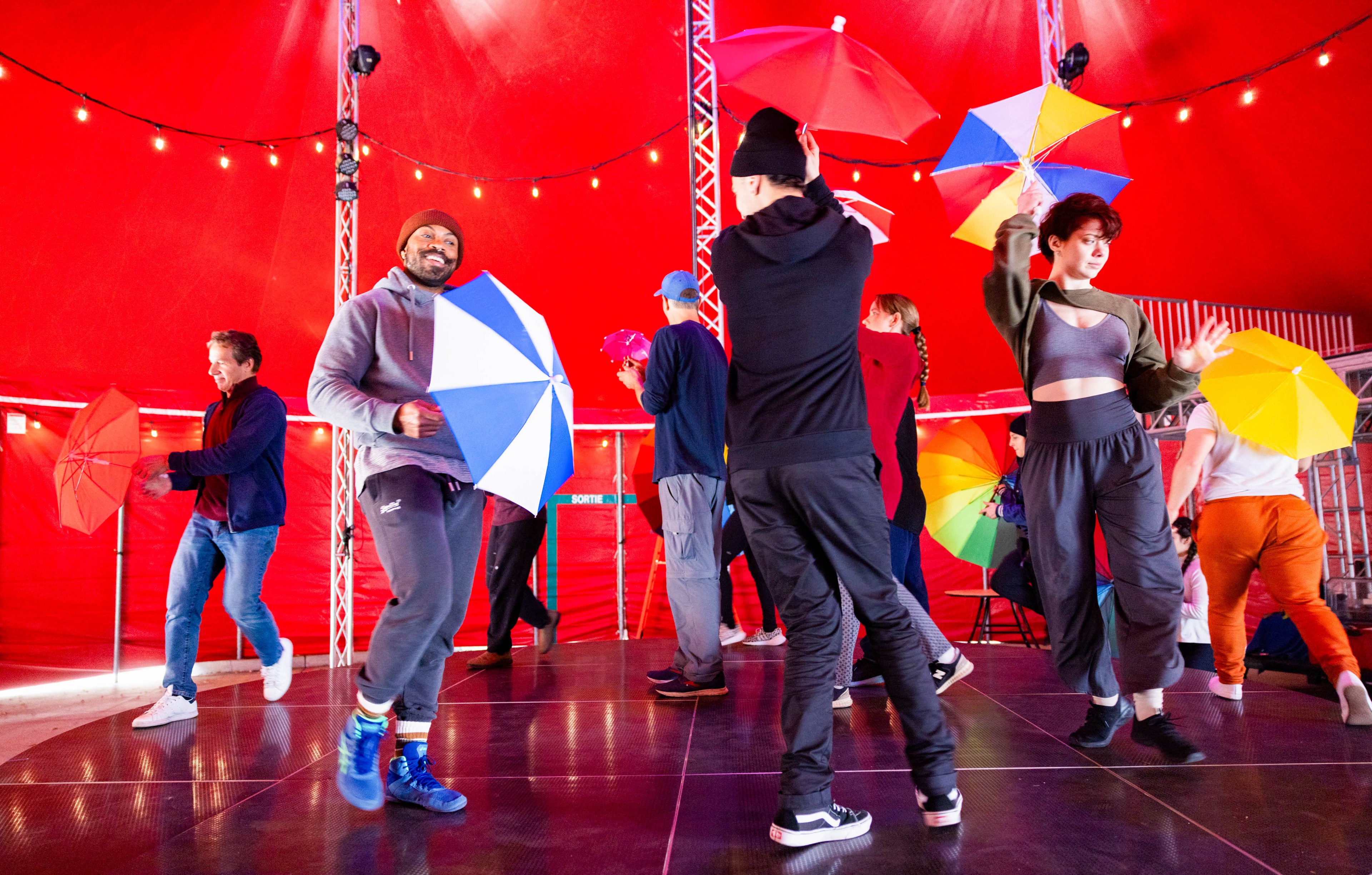 People practice with umbrellas on stage.