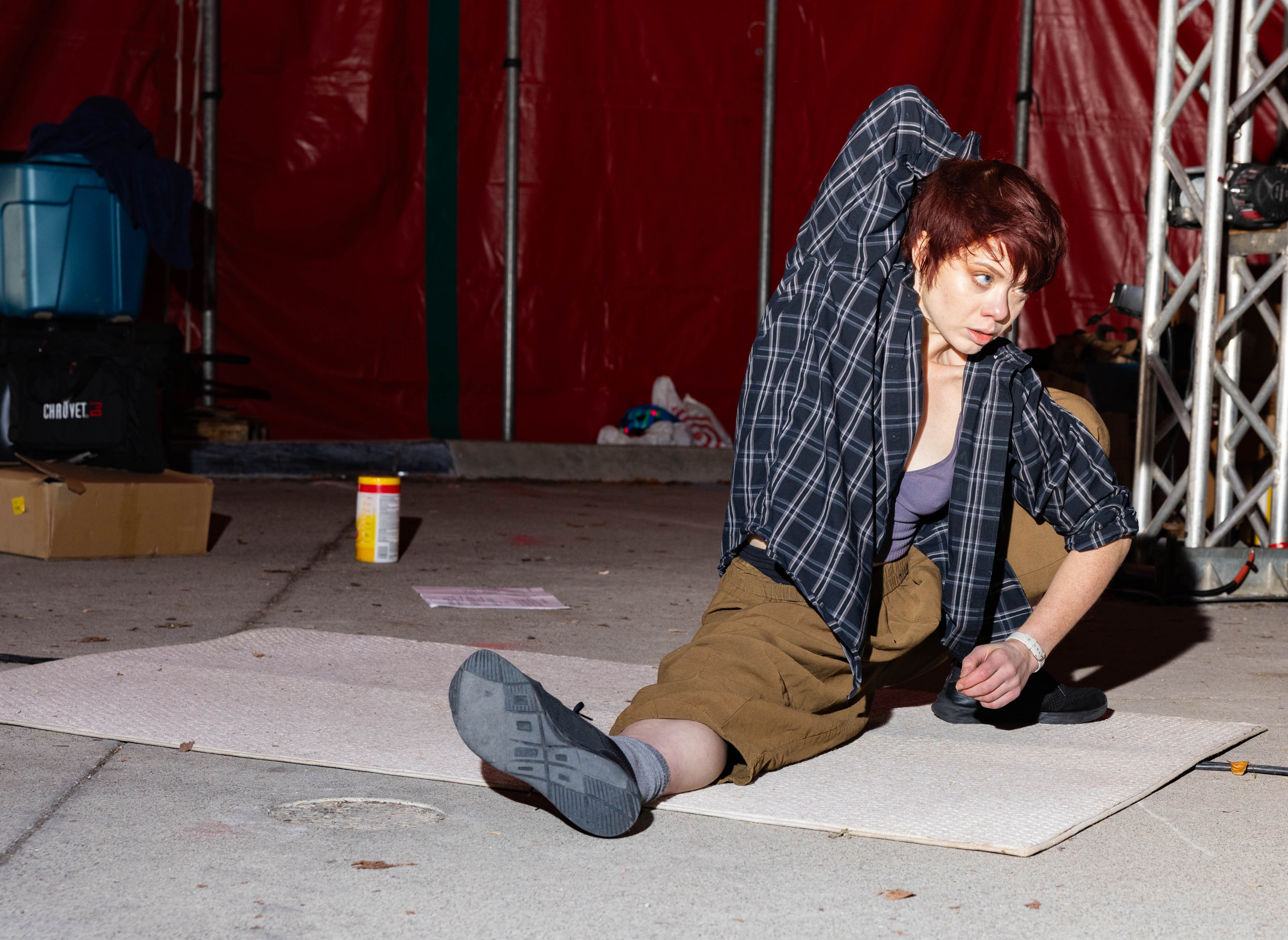 A person with a blue flannel shirt stretches on the ground.