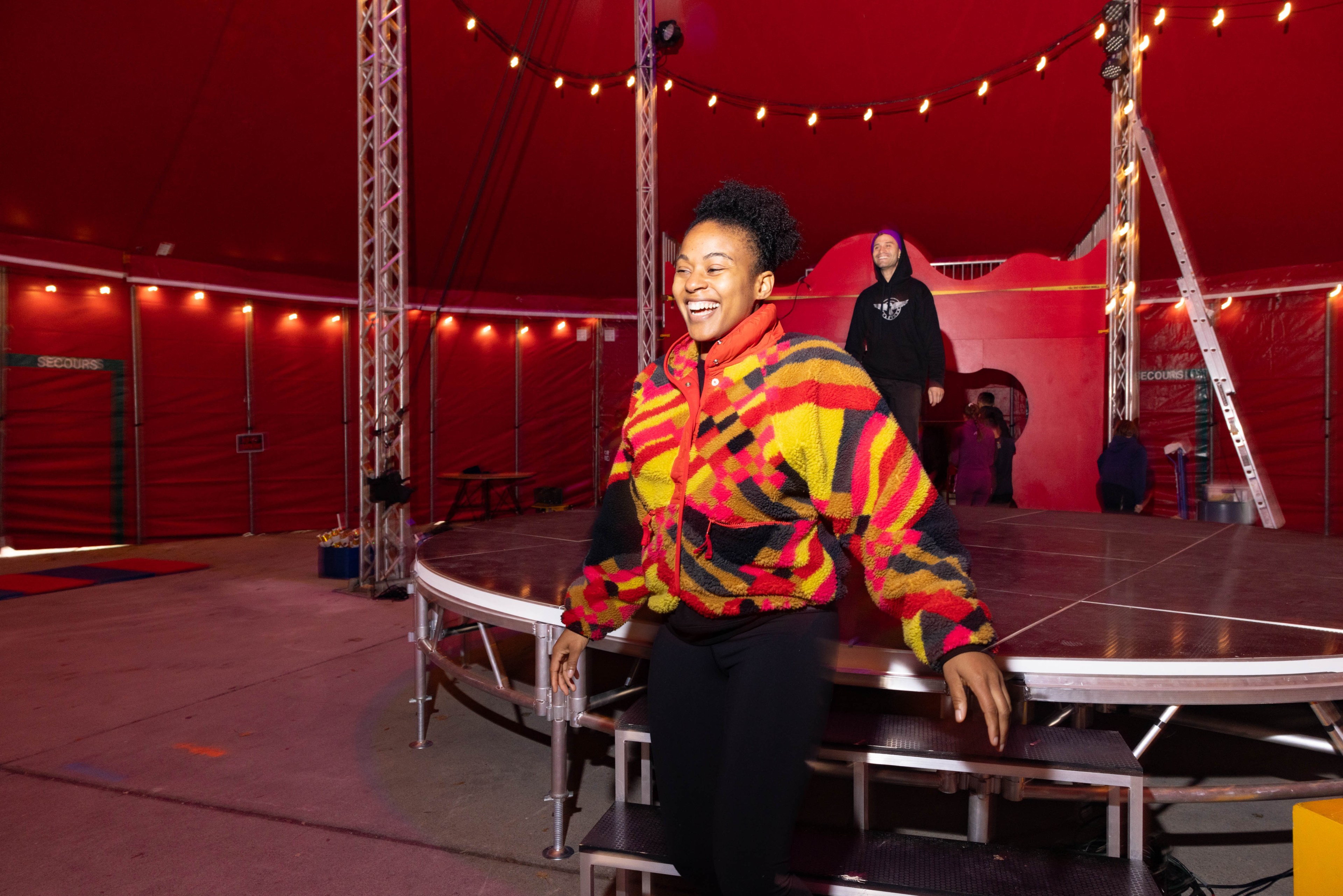 A person smiles inside a tent during circus practice.