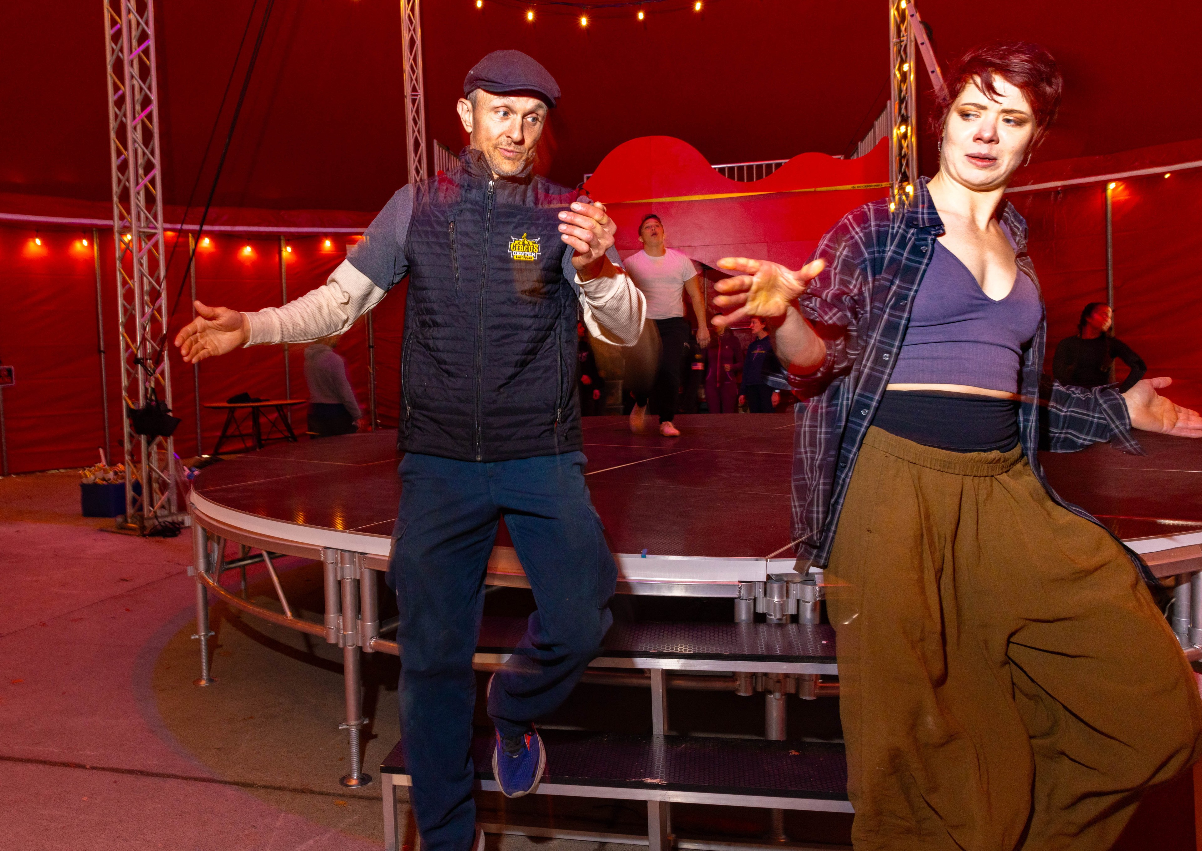 Two people practice inside inside a red circus tent.