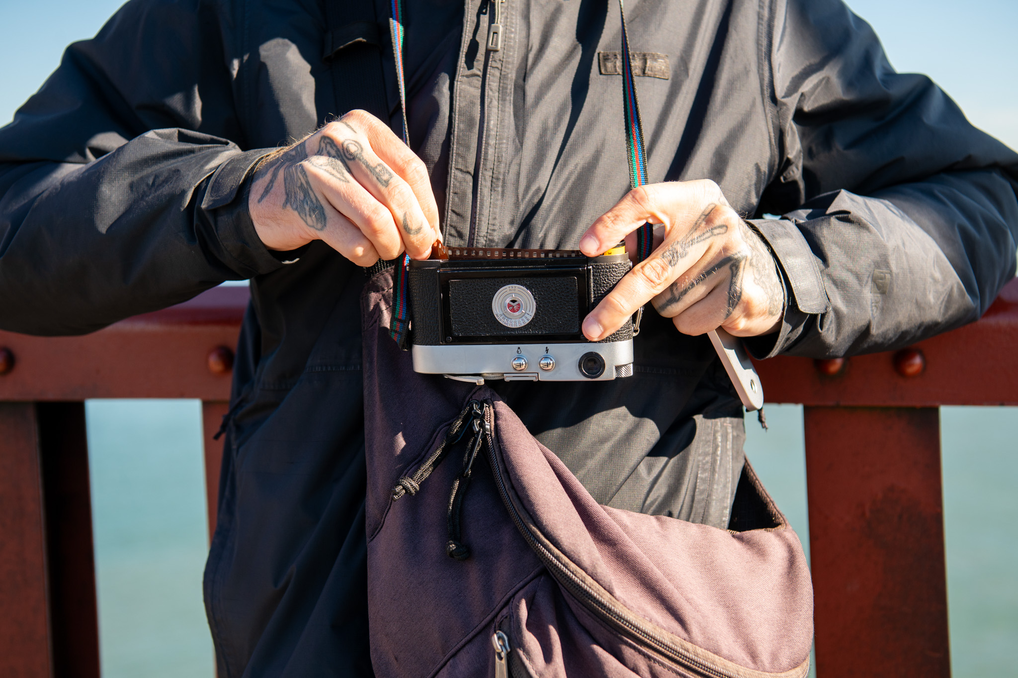 Jake Ricker loads a fresh roll of film into his camera on the pedestrian walkway of the Golden Gate Bridge on Monday, Dec. 12, 2023. Ricker currently has around 1,000 rolls of undeveloped film from the last two years of working on his photo project.