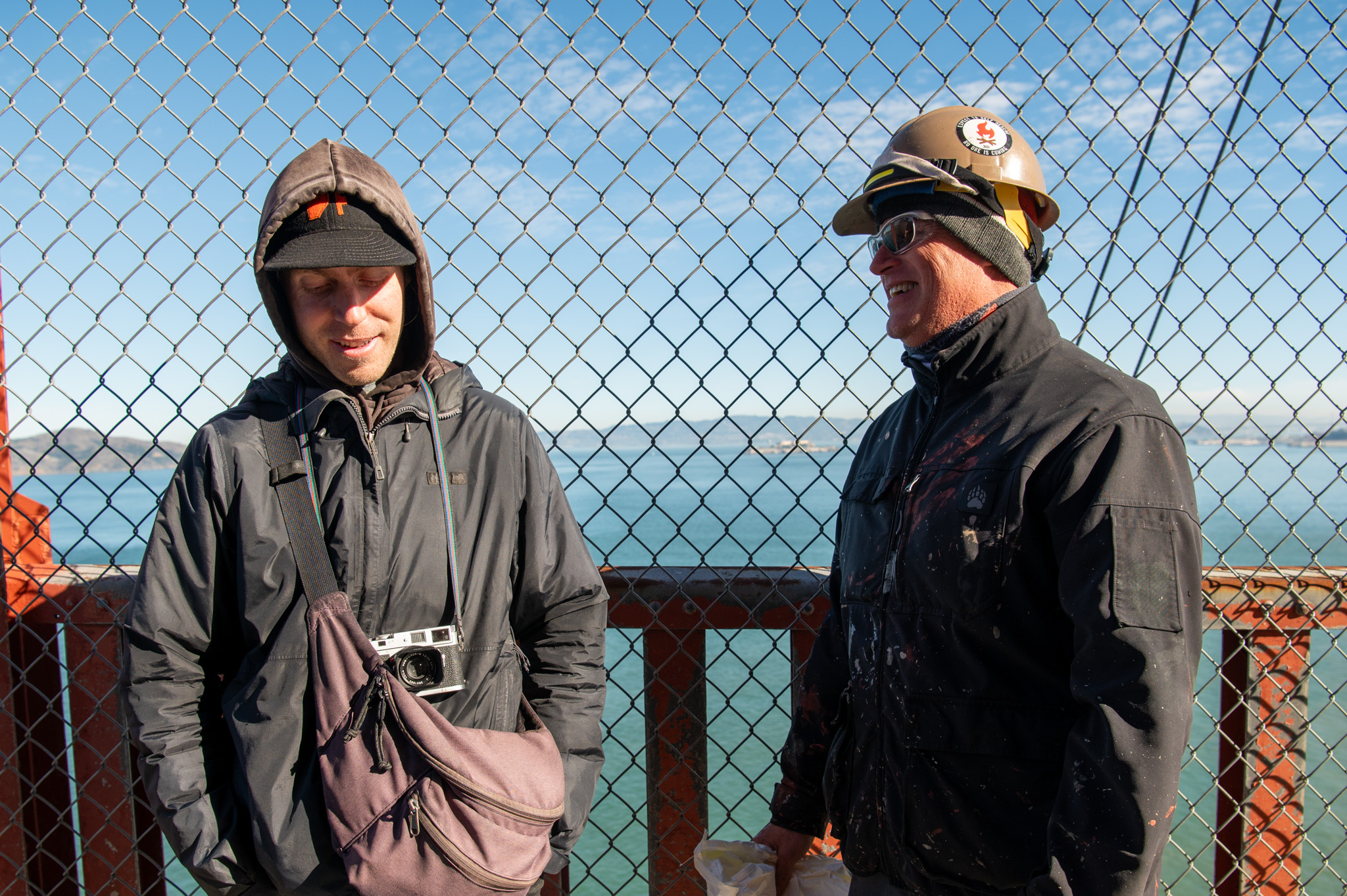 Jake Ricker, left, talks with a Golden Gate Bridge painter named Jay on the bridge’s pedestrian walkway on Monday, Dec. 12, 2023.