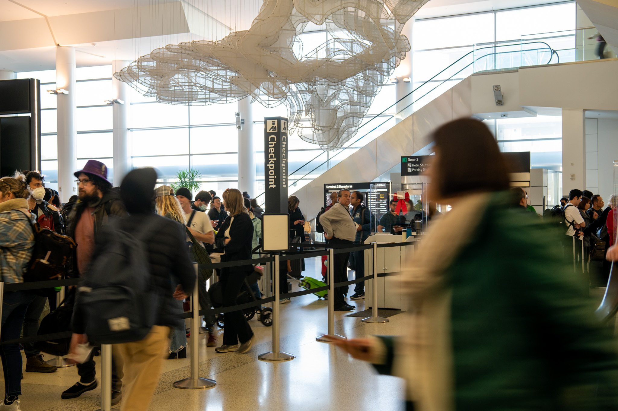 A security checkpoint as people wait in line and TSA agents checking boarding passes and id's.
