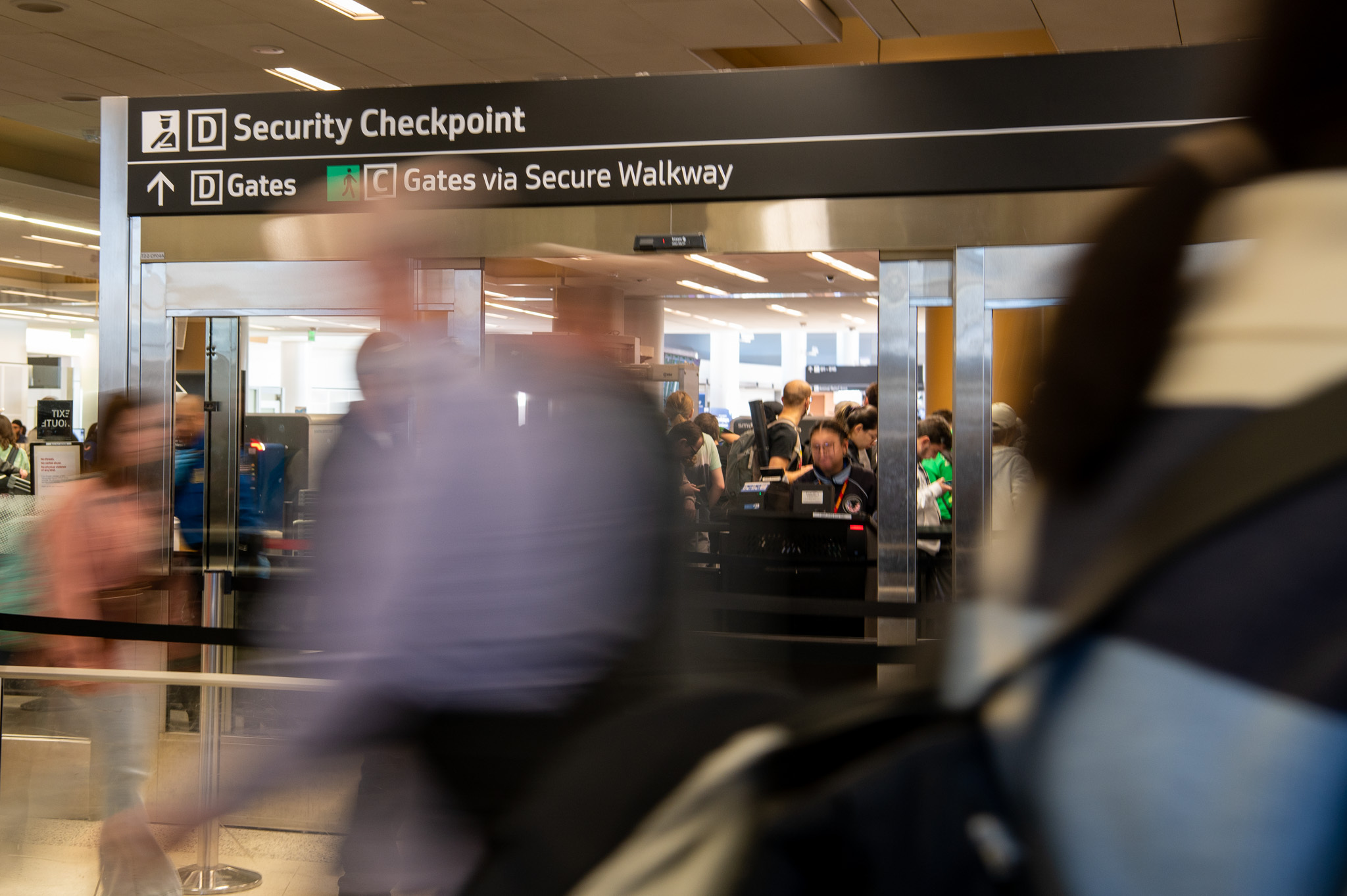 A security checkpoint as people wait in line and TSA agents checking boarding passes and id's.
