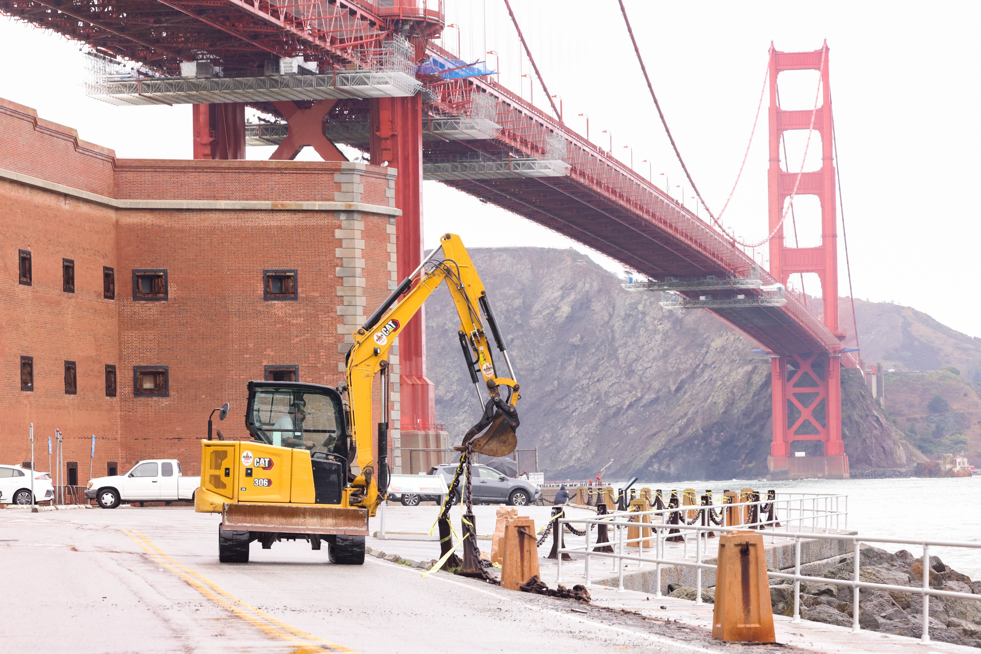 An excavator demolishes metal chains that act as guard rails at Fort Point near the Golden Gate Bridge.