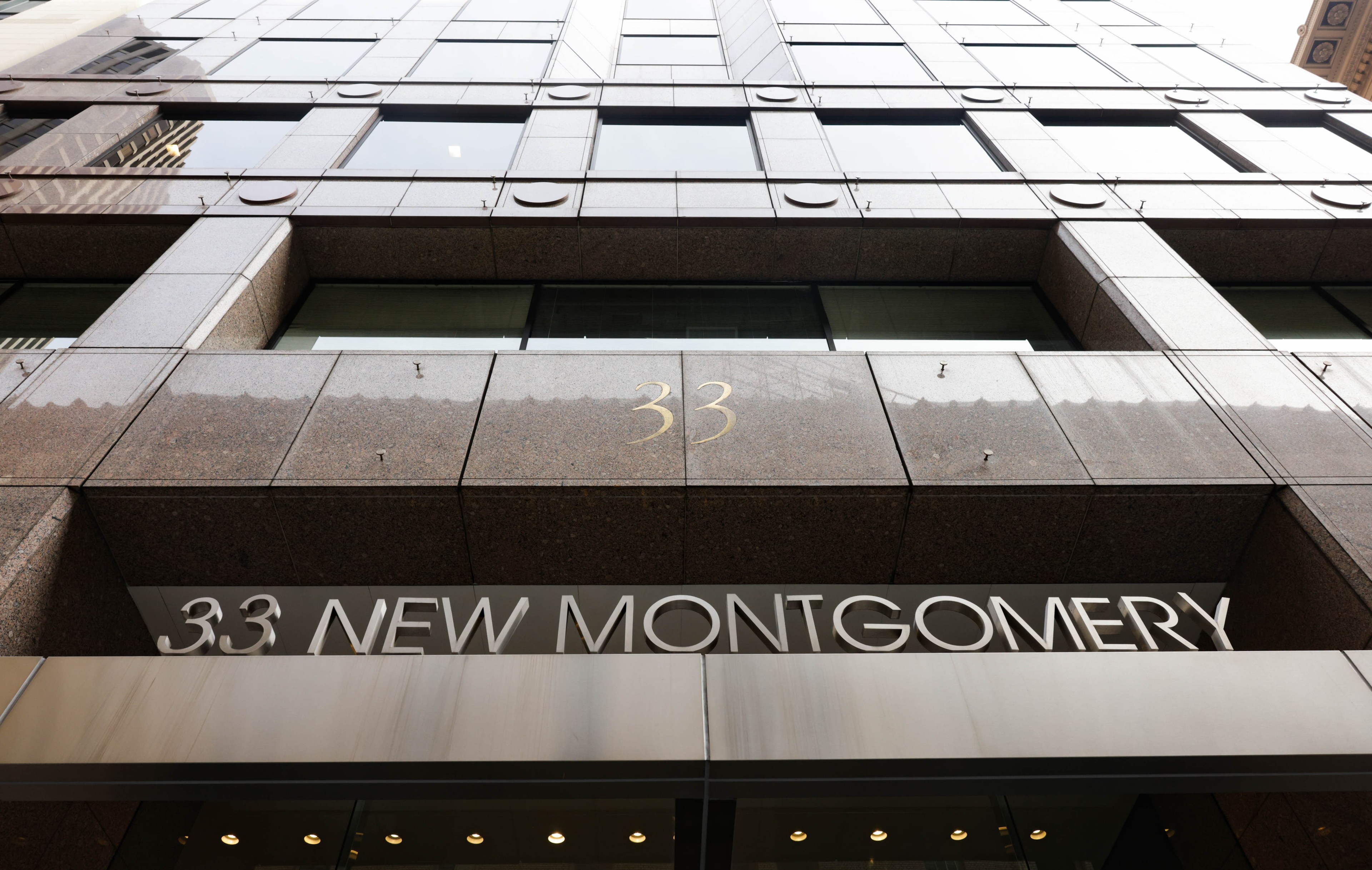 An office building with brown and gray marble with 33 New Montgomery in letters.