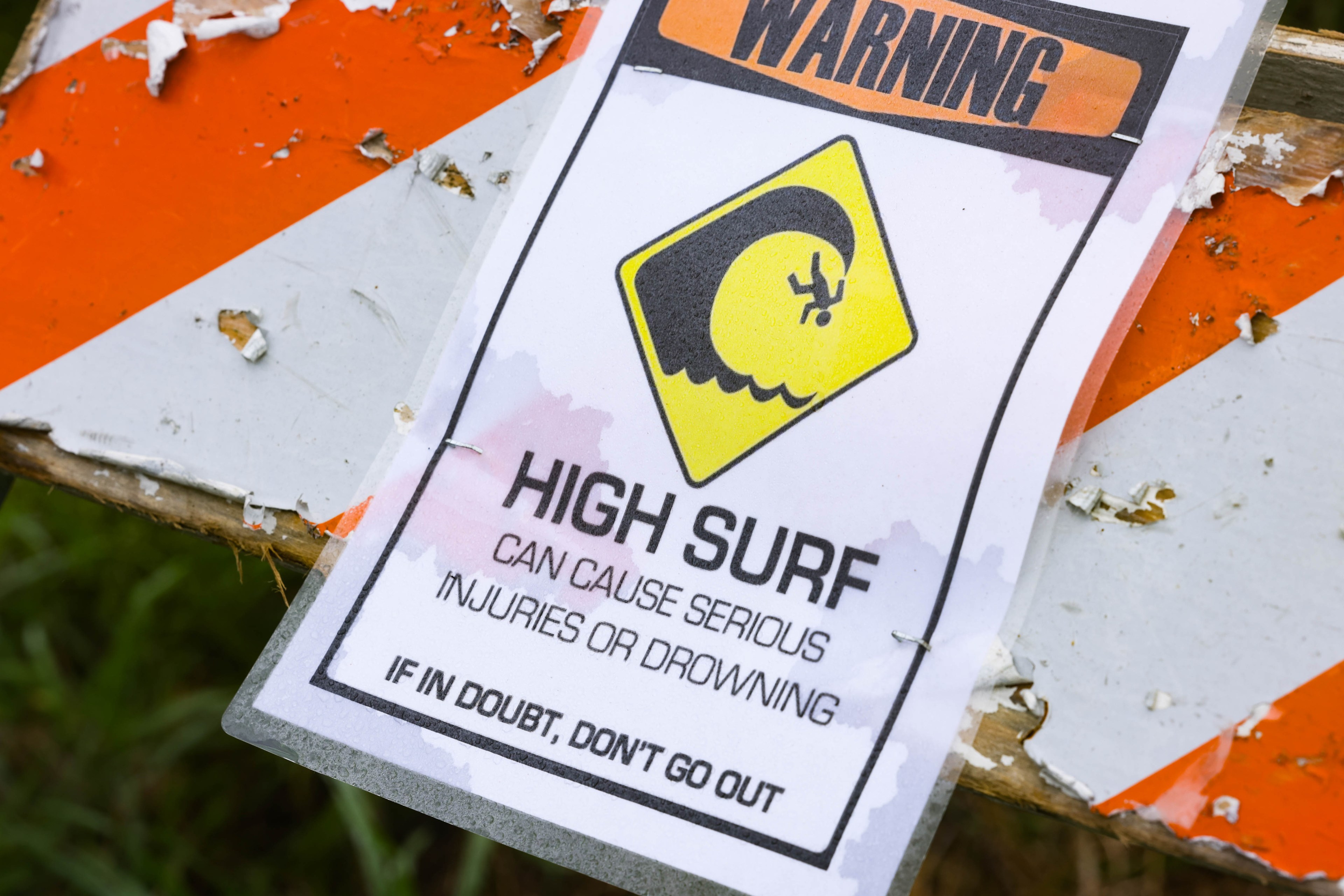 A sign that reads high surf during a storm along the California coast.