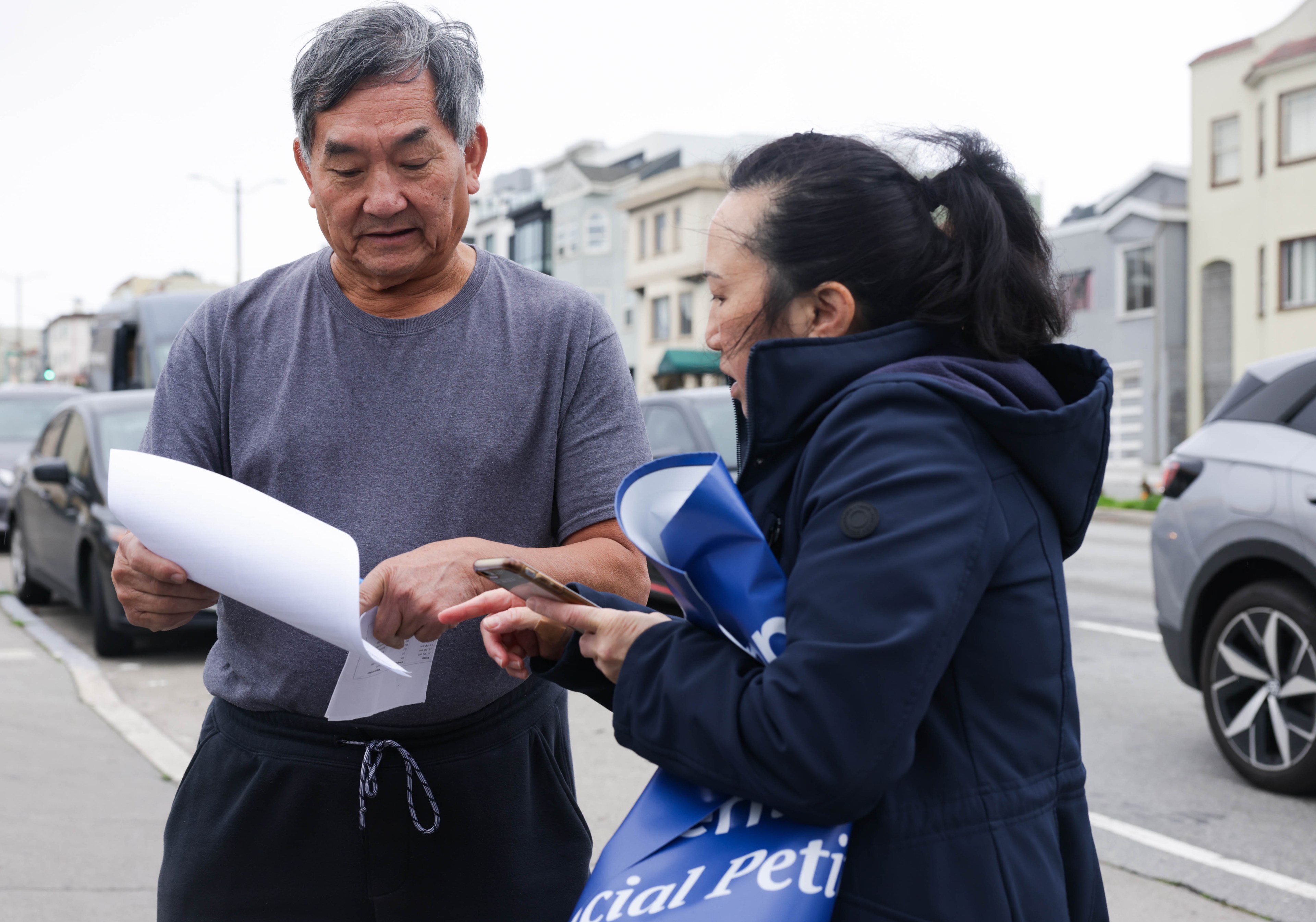 A volunteer helps a man sign a petition on Taraval Street in San Francisco.