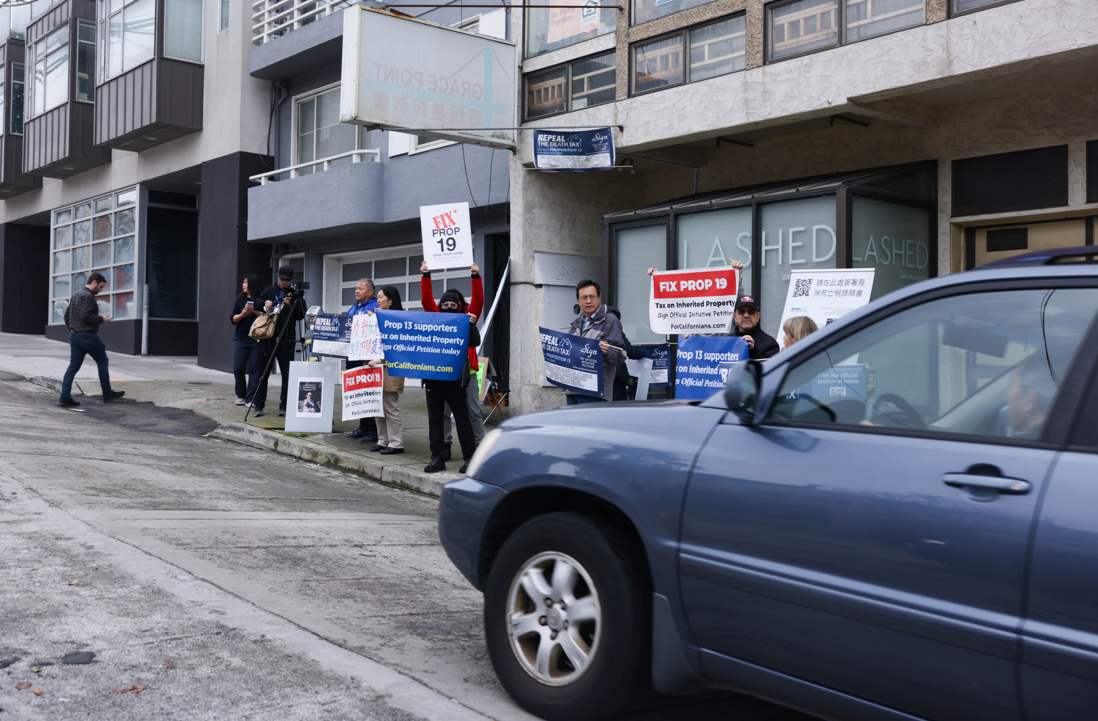 Protesters to Prop. 19 wave signs to a car passing by on Taraval Street.