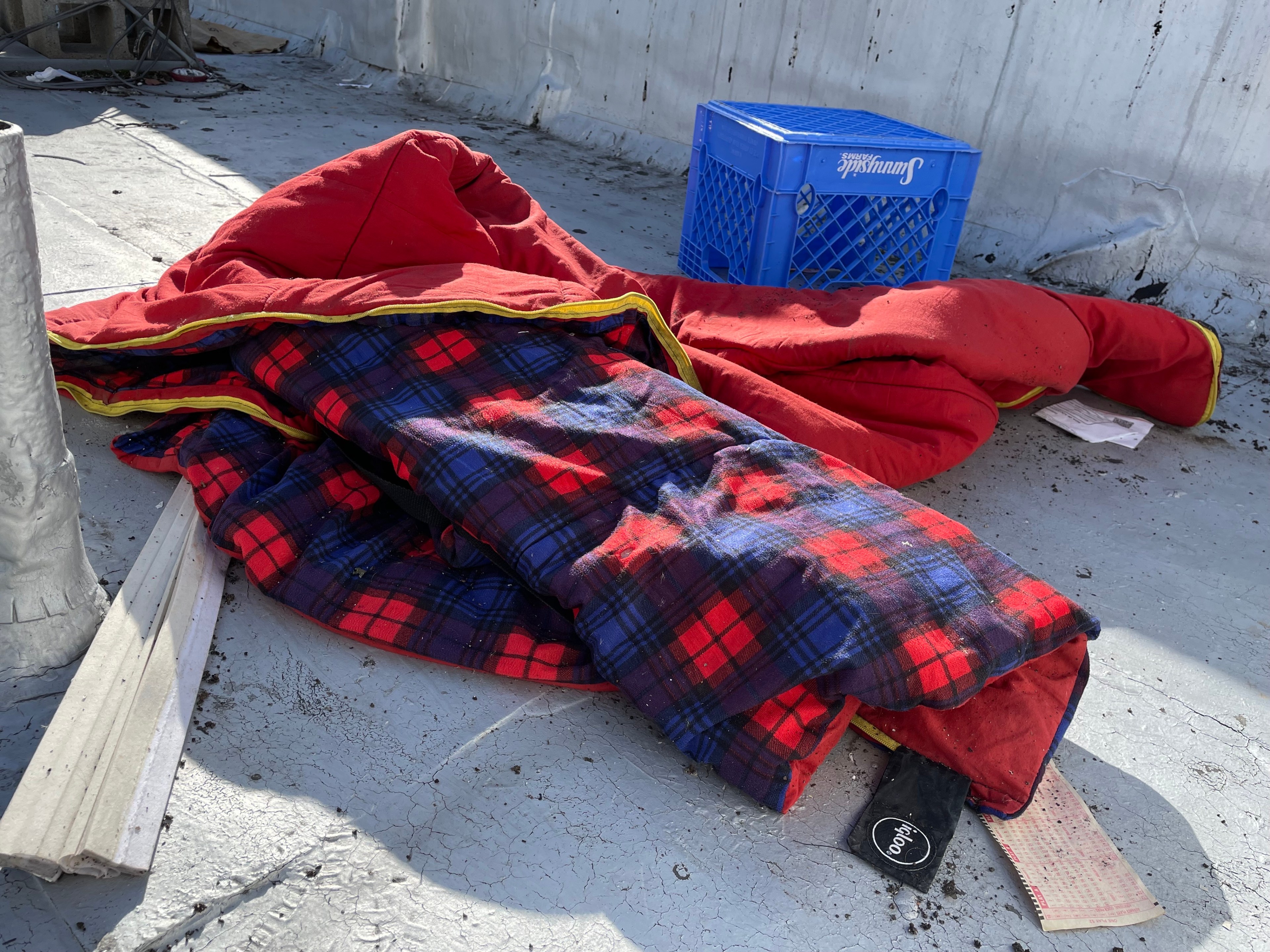 A red sleeping bag is seen on the floor.