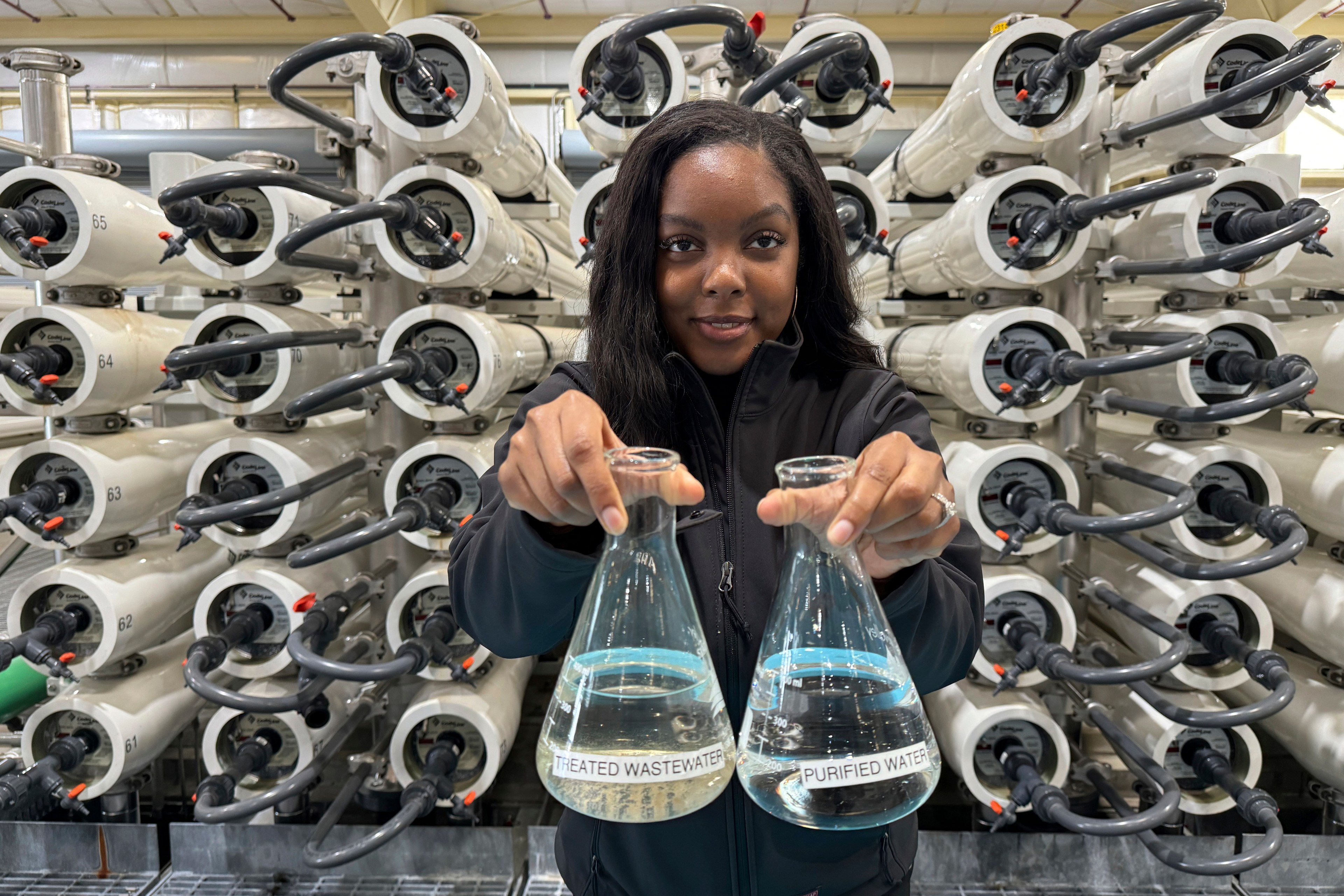 A woman holds two beakers filled with water