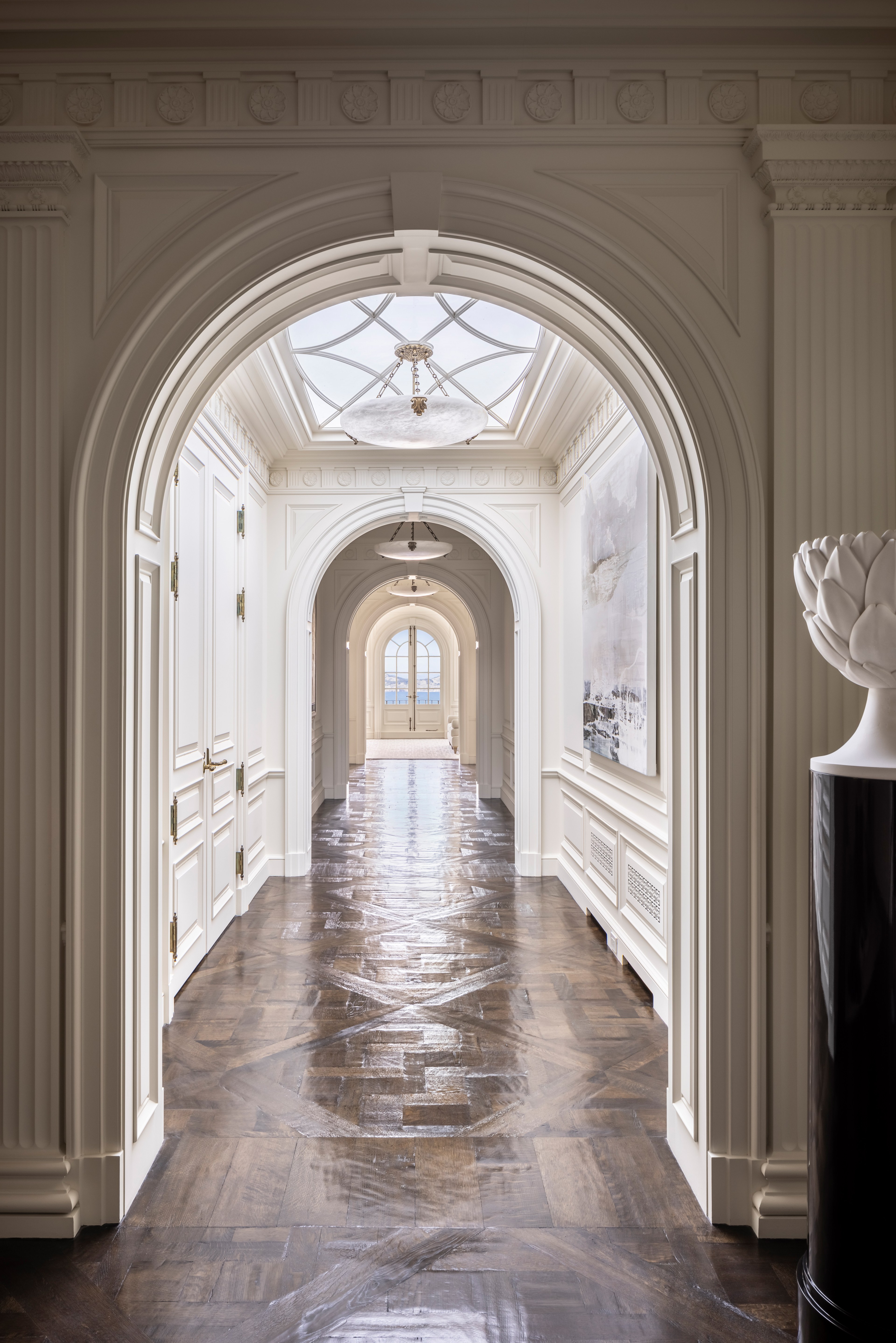 An arched entryway leads into a white-painted wooden-floored hall.