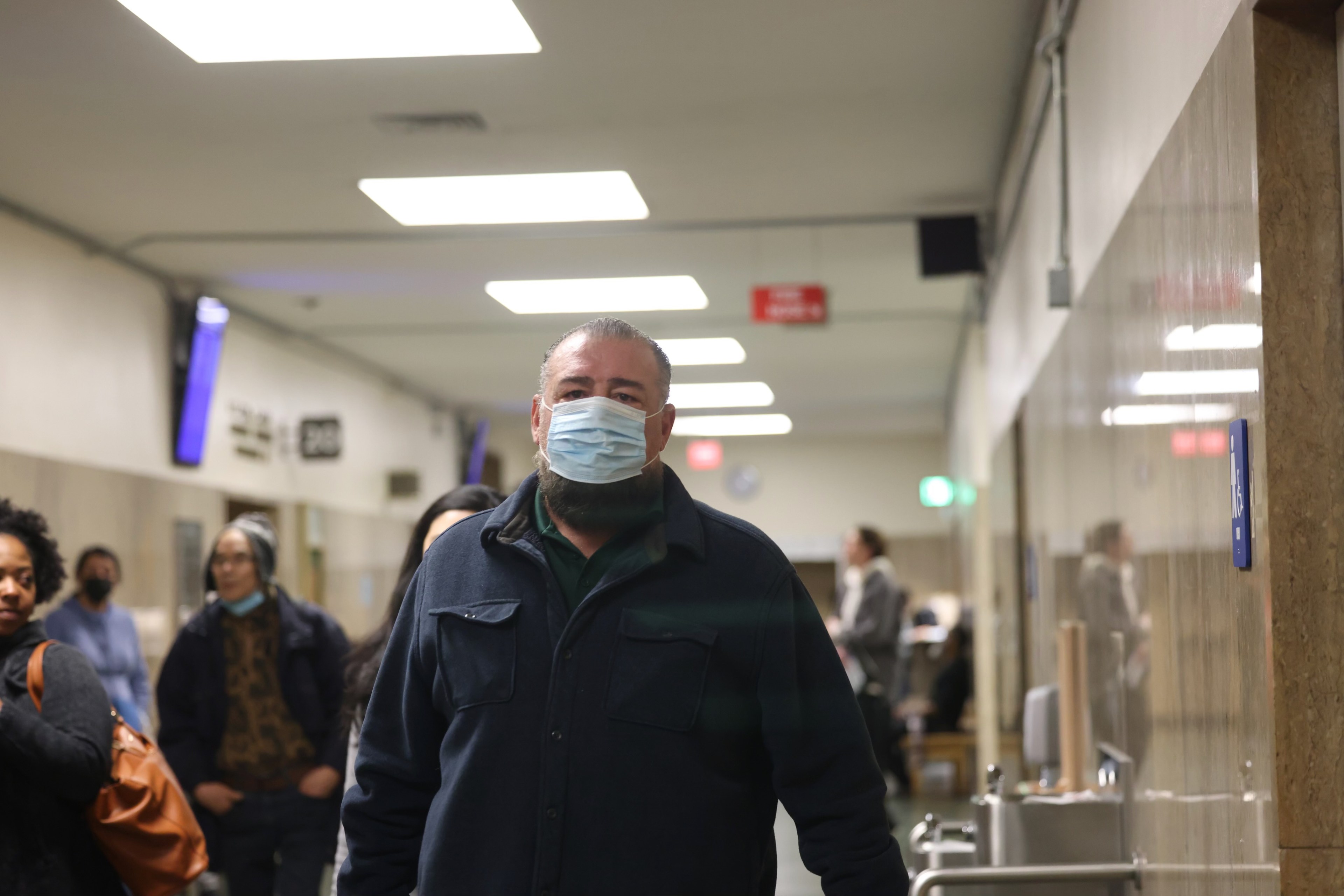Fomer SFFD Commissioner Don Carmignani, wearing a face mask, walks through the hallways of the Hall of Justice in San Francisco.