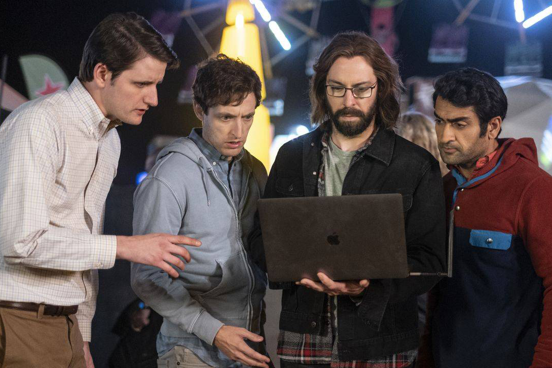 Four men look at a laptop