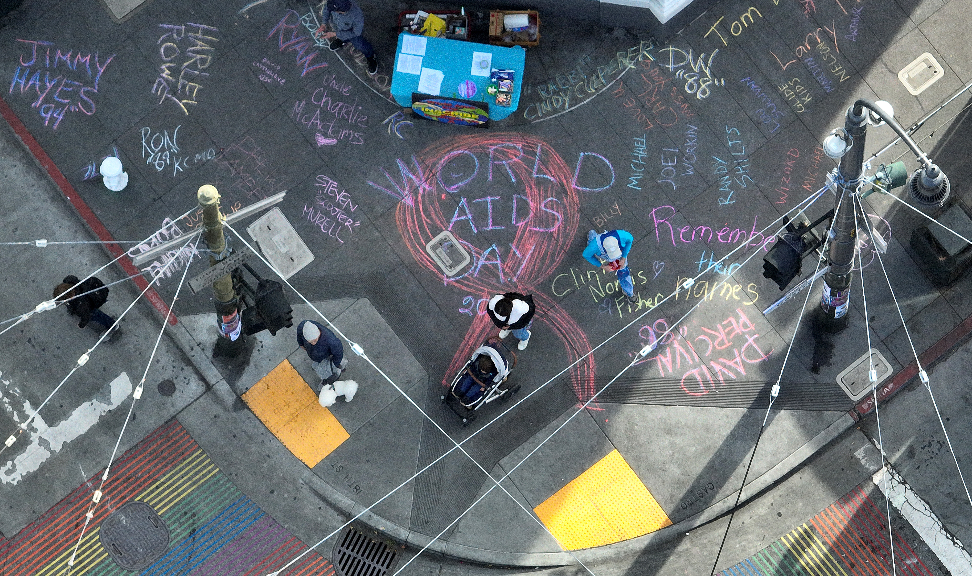 A overhead shot from above of names of people who lost their lives to Aids written in chalk on the sidewalk.