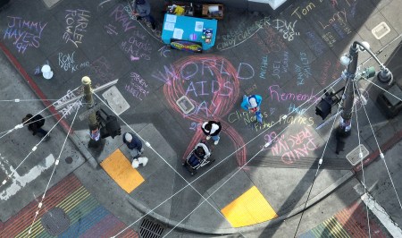 A overhead shot from above of names of people who lost their lives to Aids written in chalk on the sidewalk.